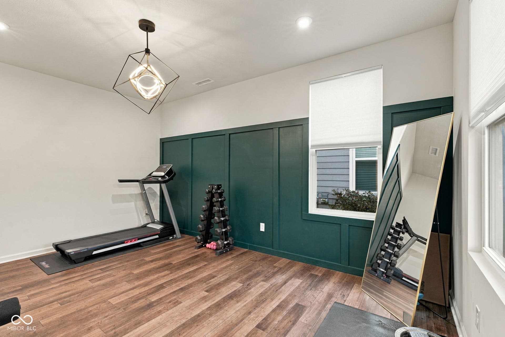 Wood-finish flooring, accent panel wall, recessed lighting, and a modern geometric pendant light fixture