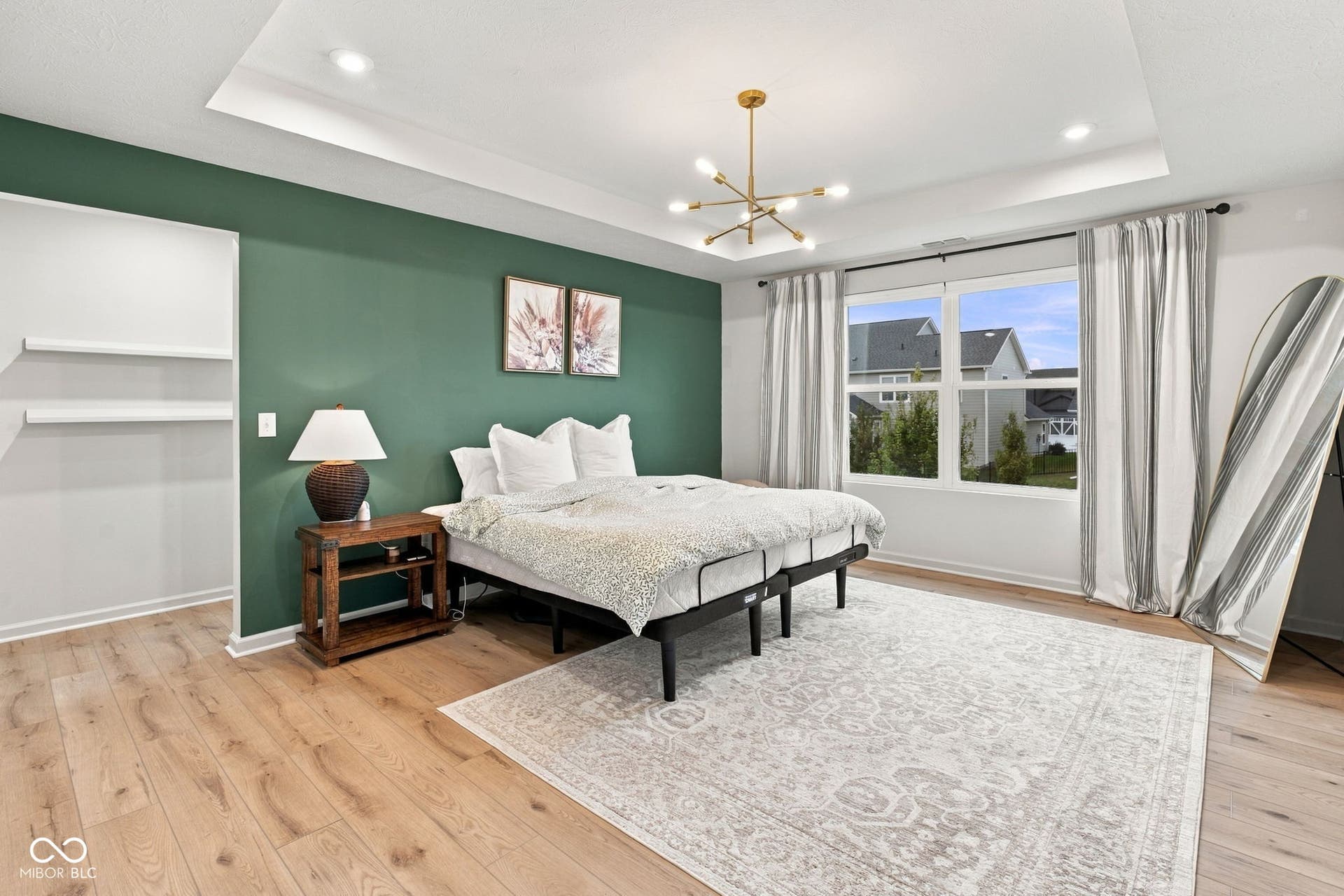 Recessed lighting, LVP flooring, tray ceiling, modern chandelier, large windows and accent wall