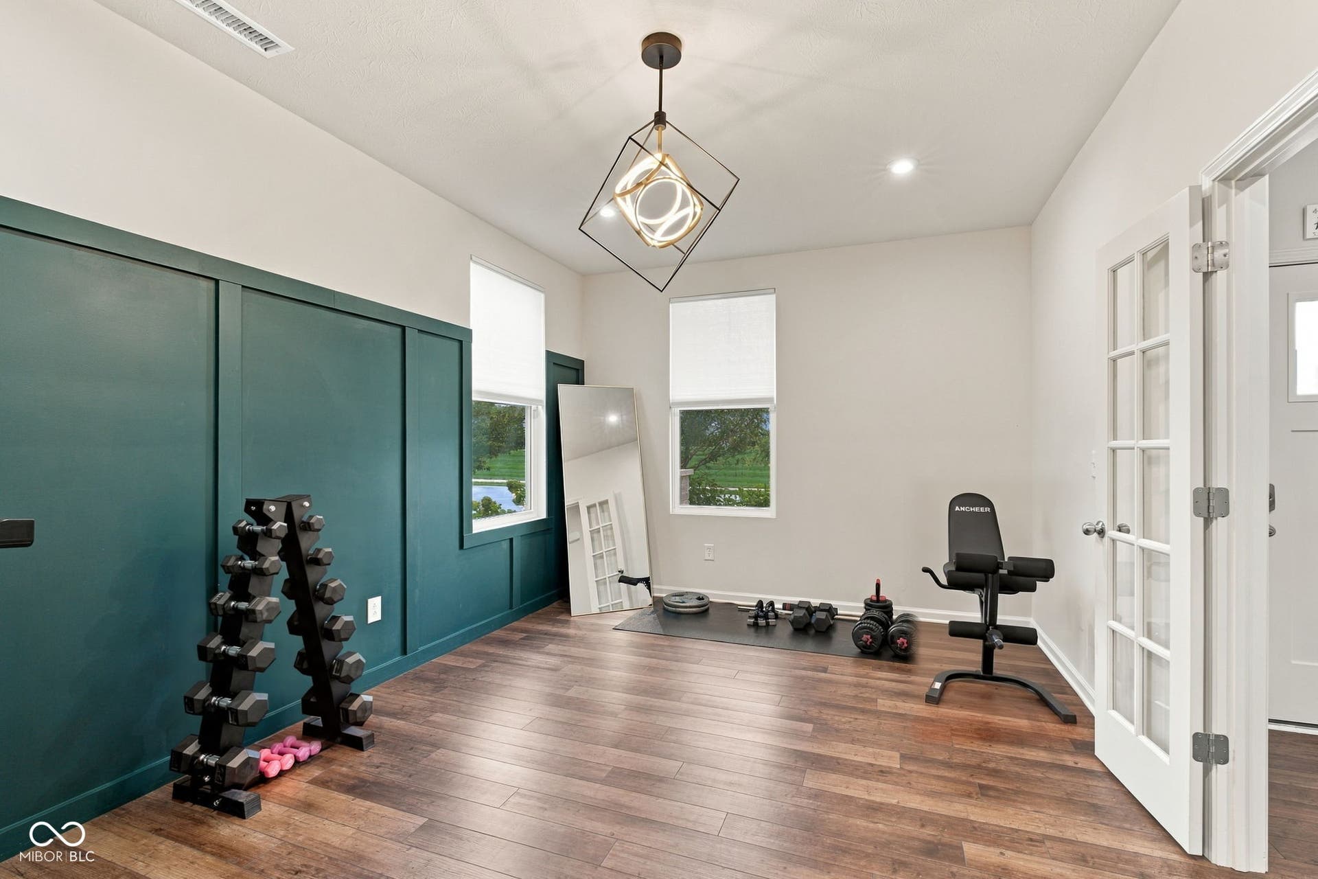 LVP flooring, custom accent wall, windows with blinds, recessed lighting, and contemporary ceiling fixture