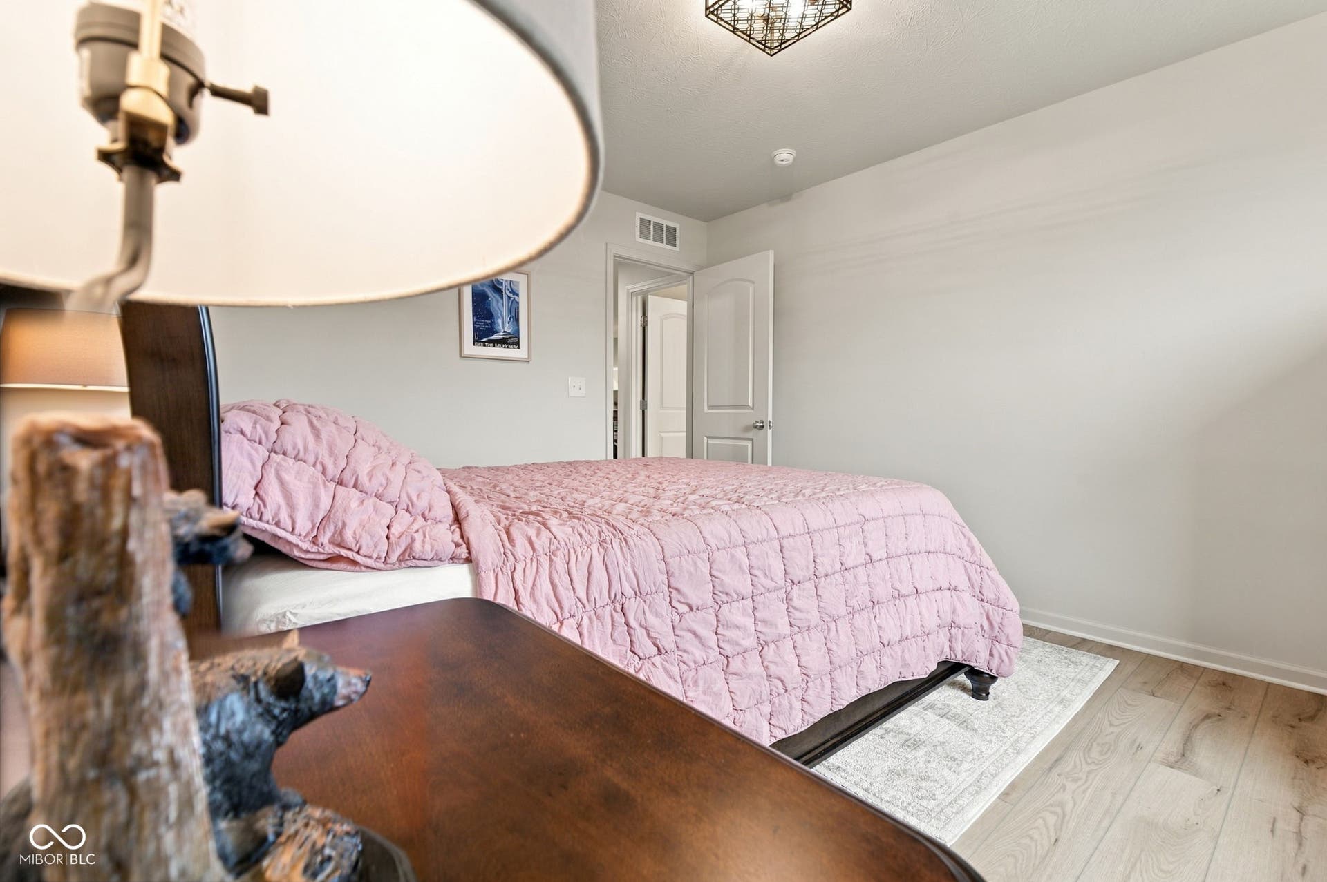Light wood-finish flooring, neutral wall color, and a ceiling-mounted light fixture