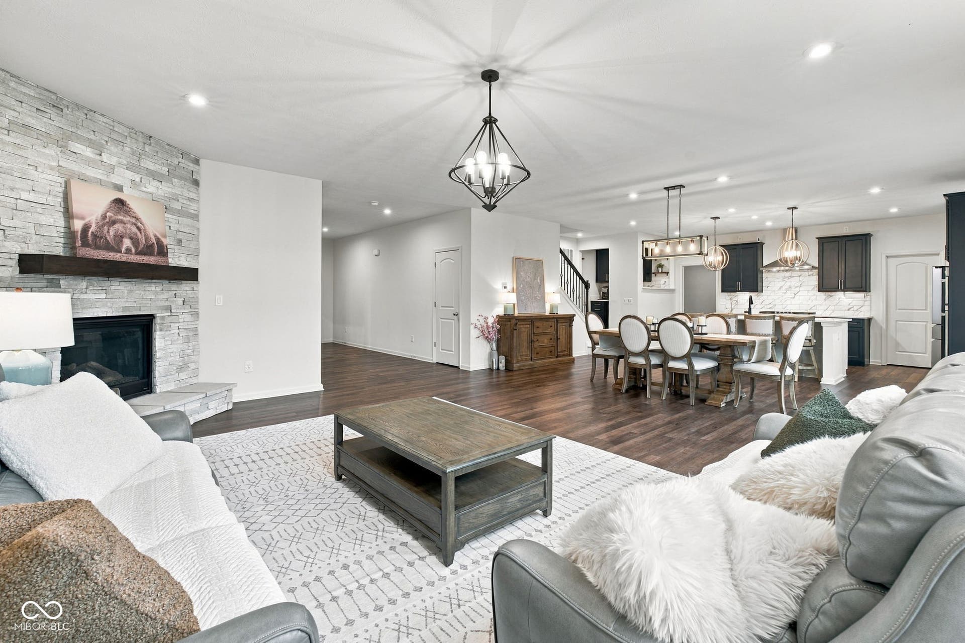 Great Room, Dining and Kitchen - Spacious open-concept living featuring wood-finish flooring, a stone-clad fireplace, recessed lighting, and a modern kitchen