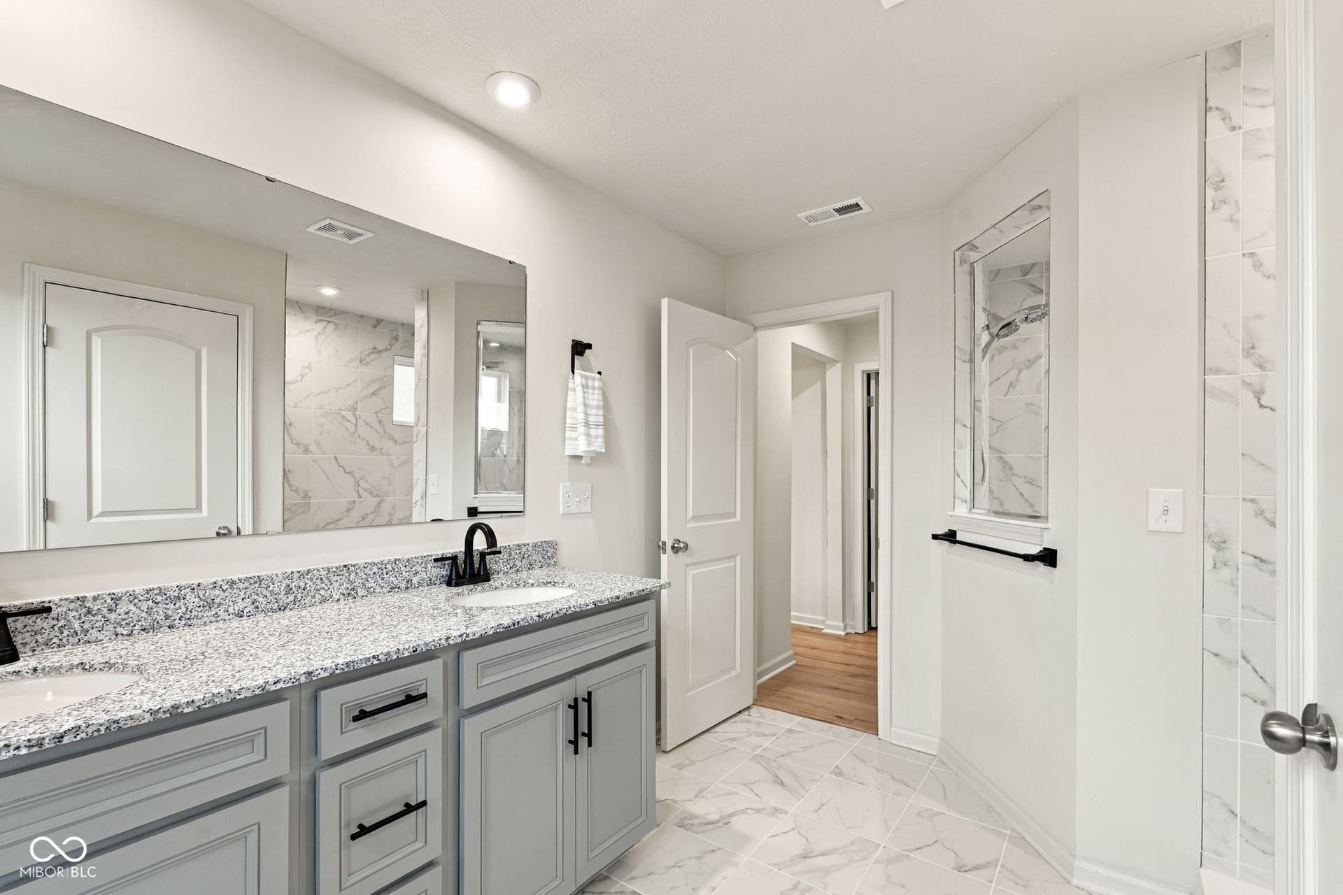 Dual vanity with light gray cabinetry and speckled countertops