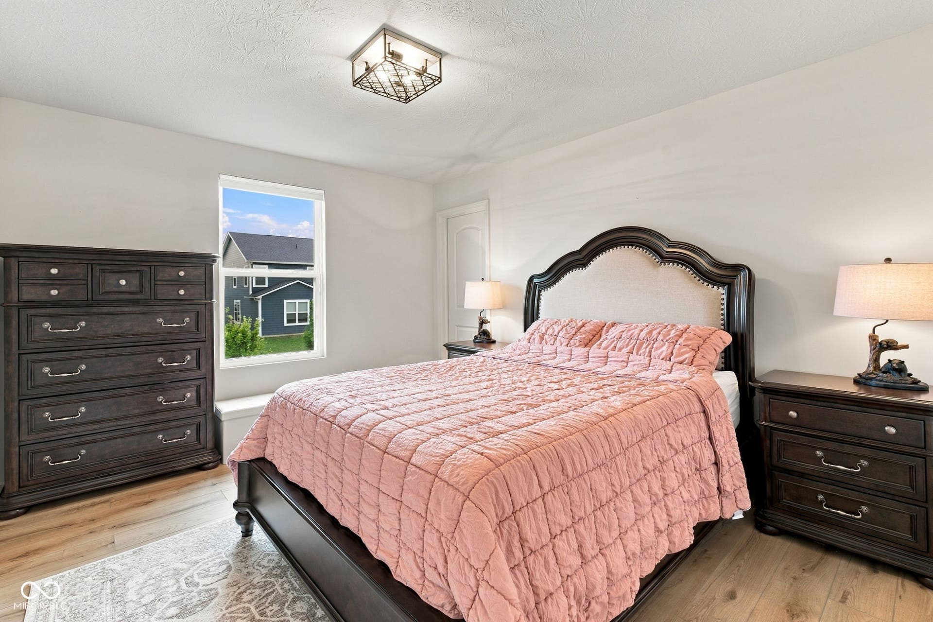 Natural light-filled room with light wood-finish flooring, a contemporary ceiling light fixture, and a window with white trim