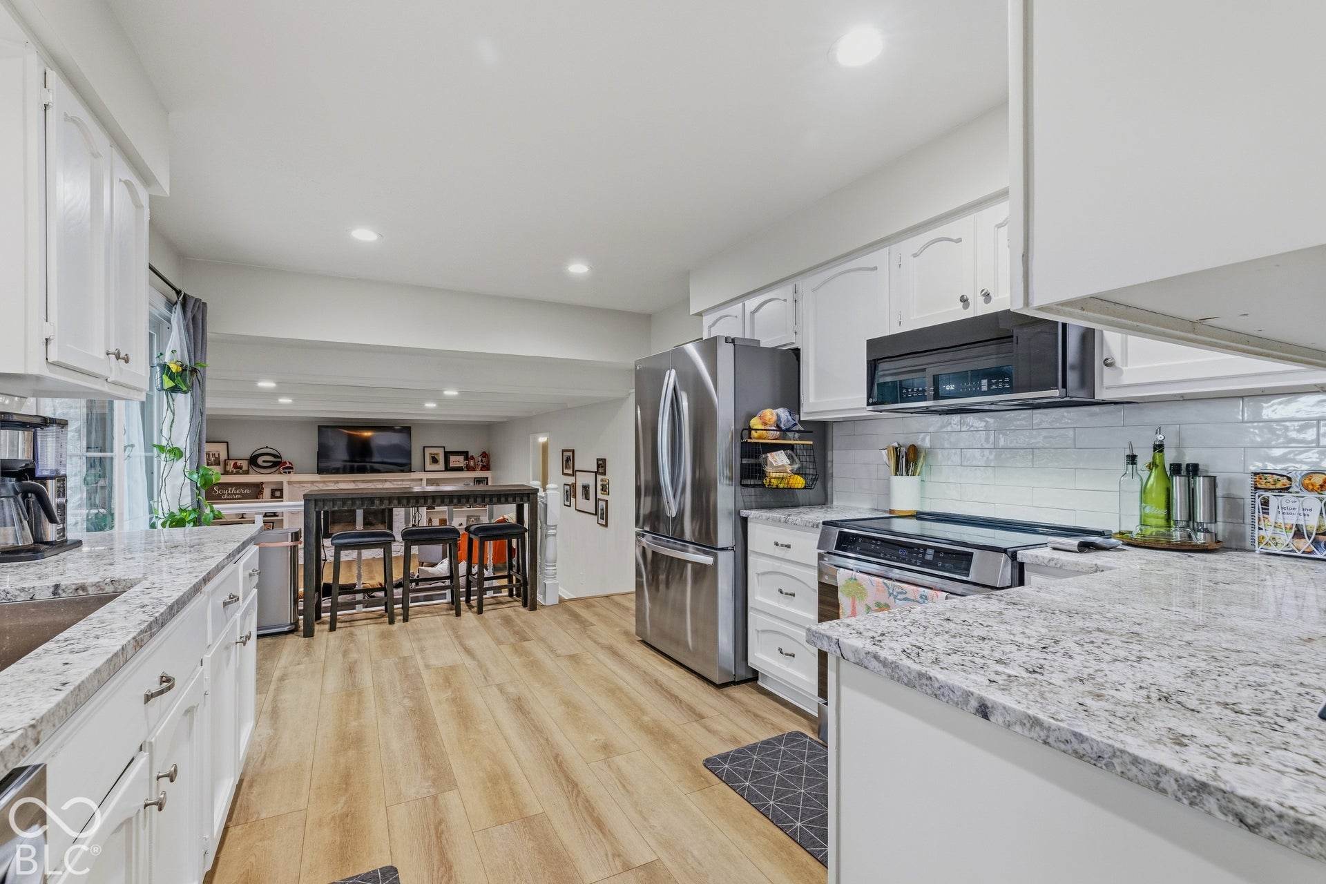 Kitchen featuring wood-finish flooring, white cabinetry, granite countertops, and a subway tile backsplash
