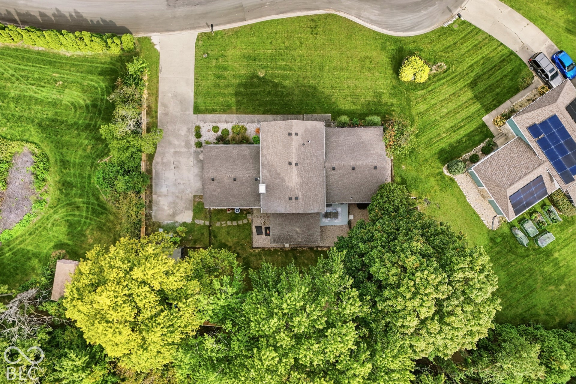 Asphalt shingle roof, concrete driveway, stone pathway, and surrounding green landscaping