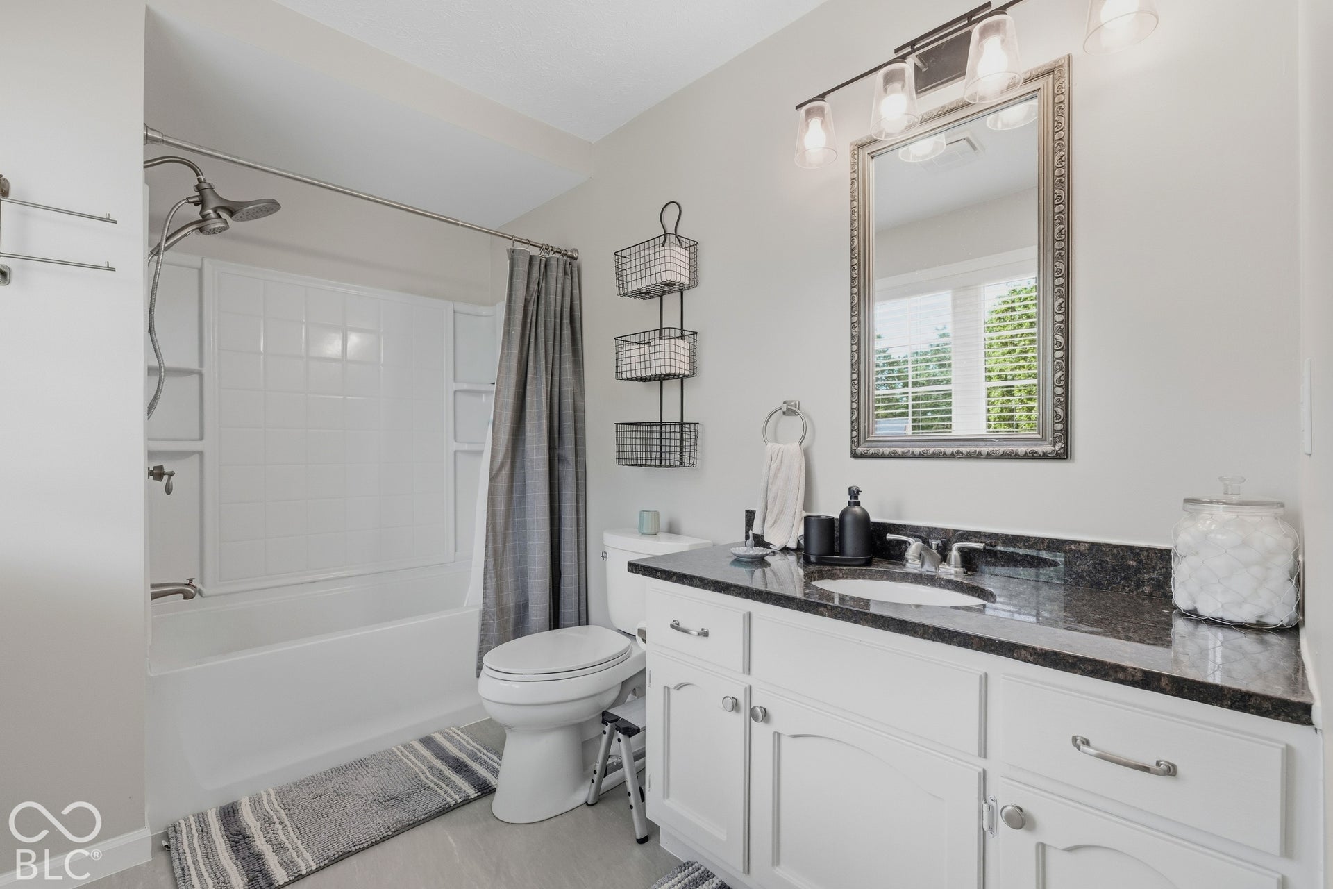 White vanity with undermount sink, dark speckled countertop, and silver fixtures