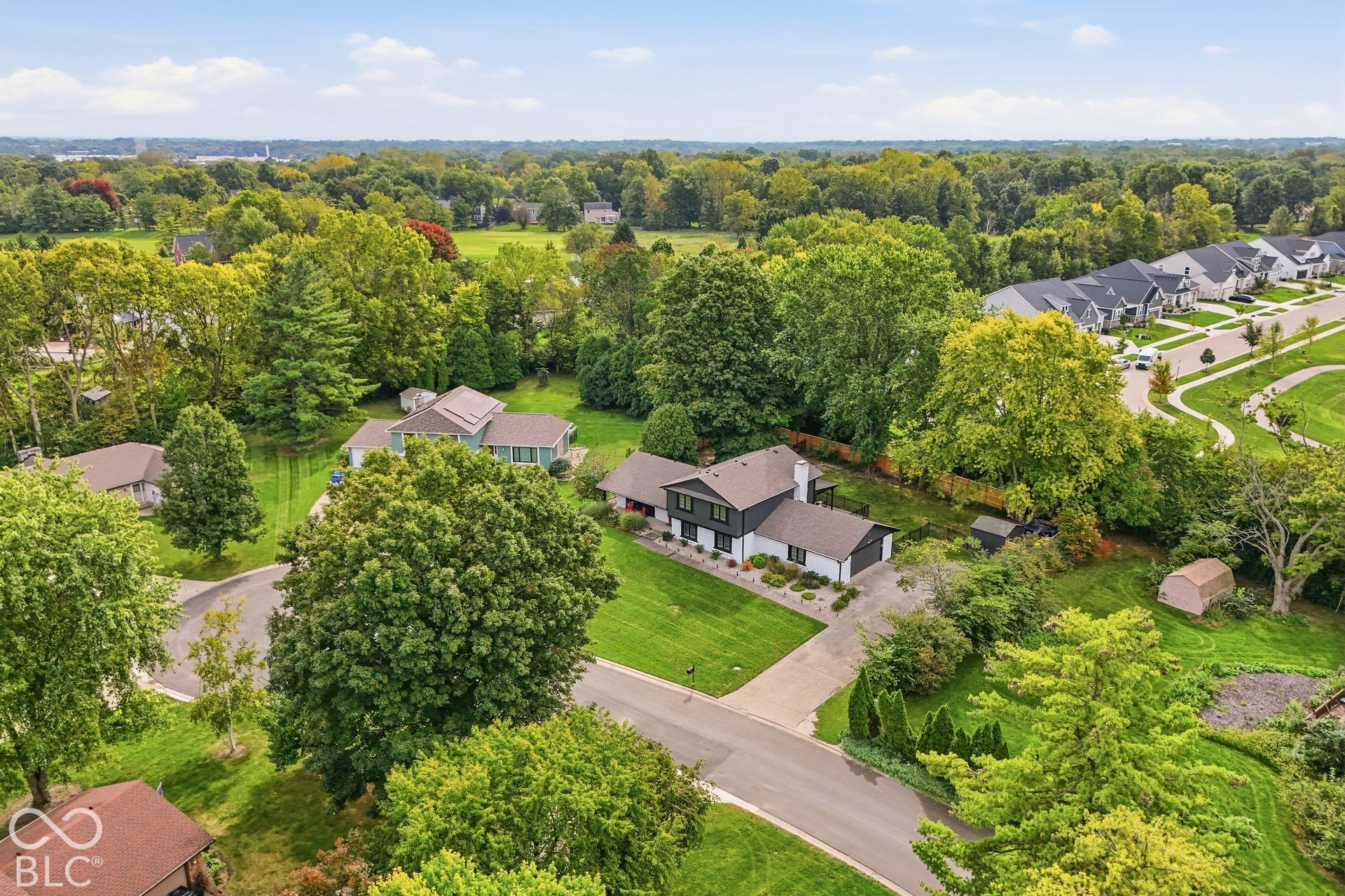 Expansive green lawn with mature trees and paved driveway