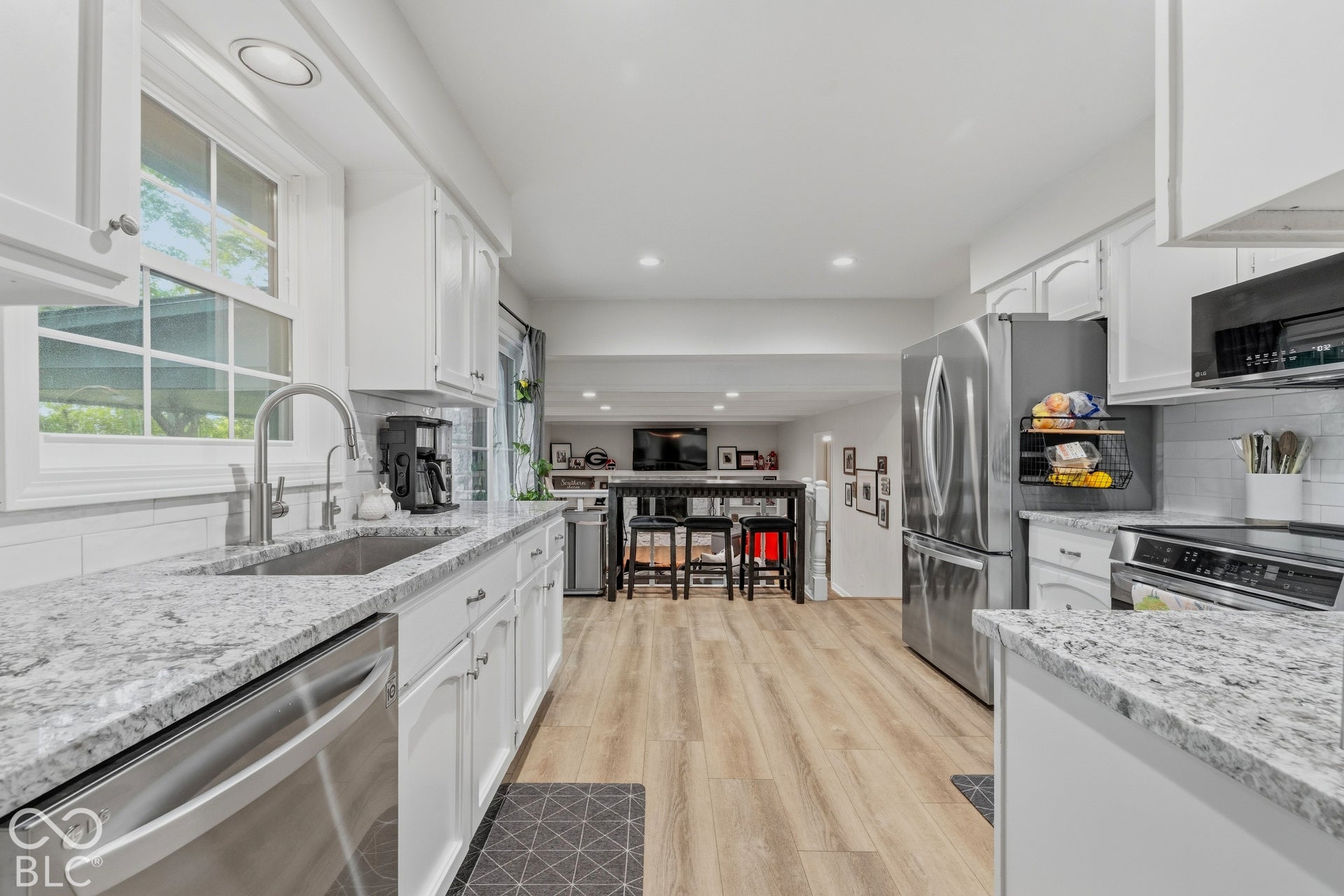 White cabinetry kitchen featuring stainless steel appliances, light-toned wood-finish flooring, and white countertops
