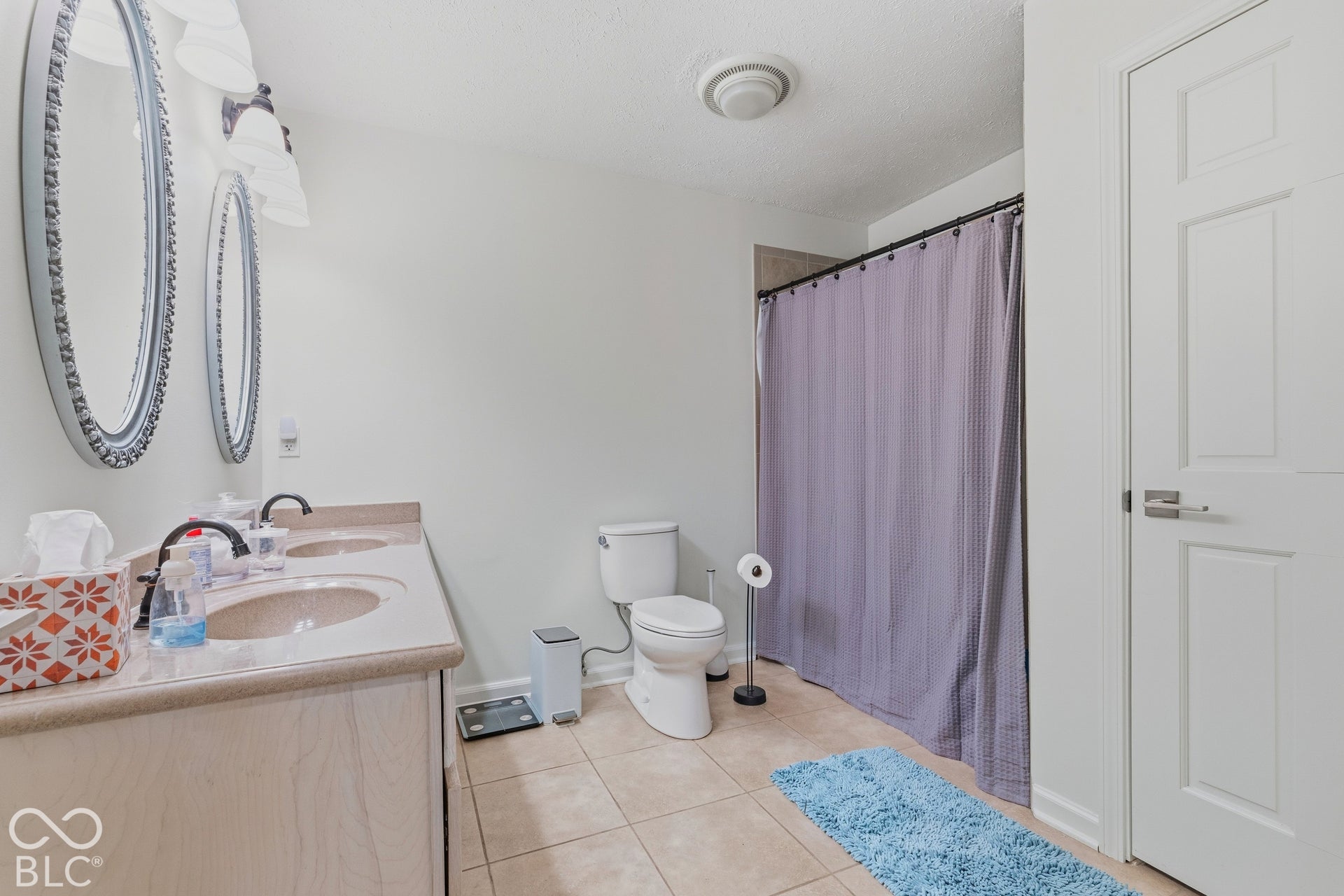 Dual vanity with integral sinks and black fixtures, framed mirrors, and tile flooring