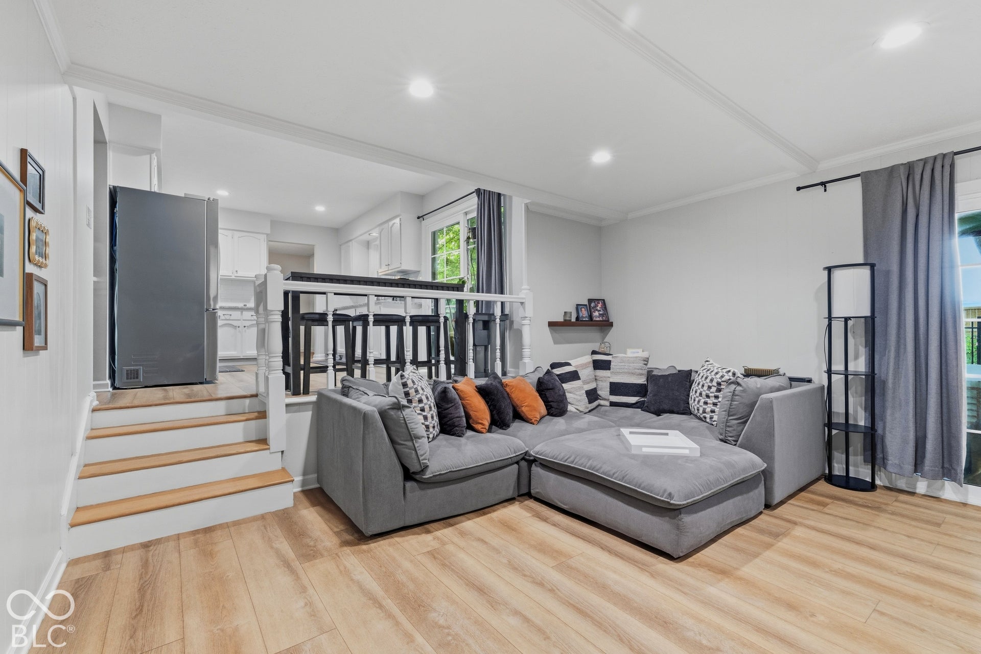 Wood-finish flooring throughout, bright recessed lighting, white crown molding, and a built-in kitchen bar with seating