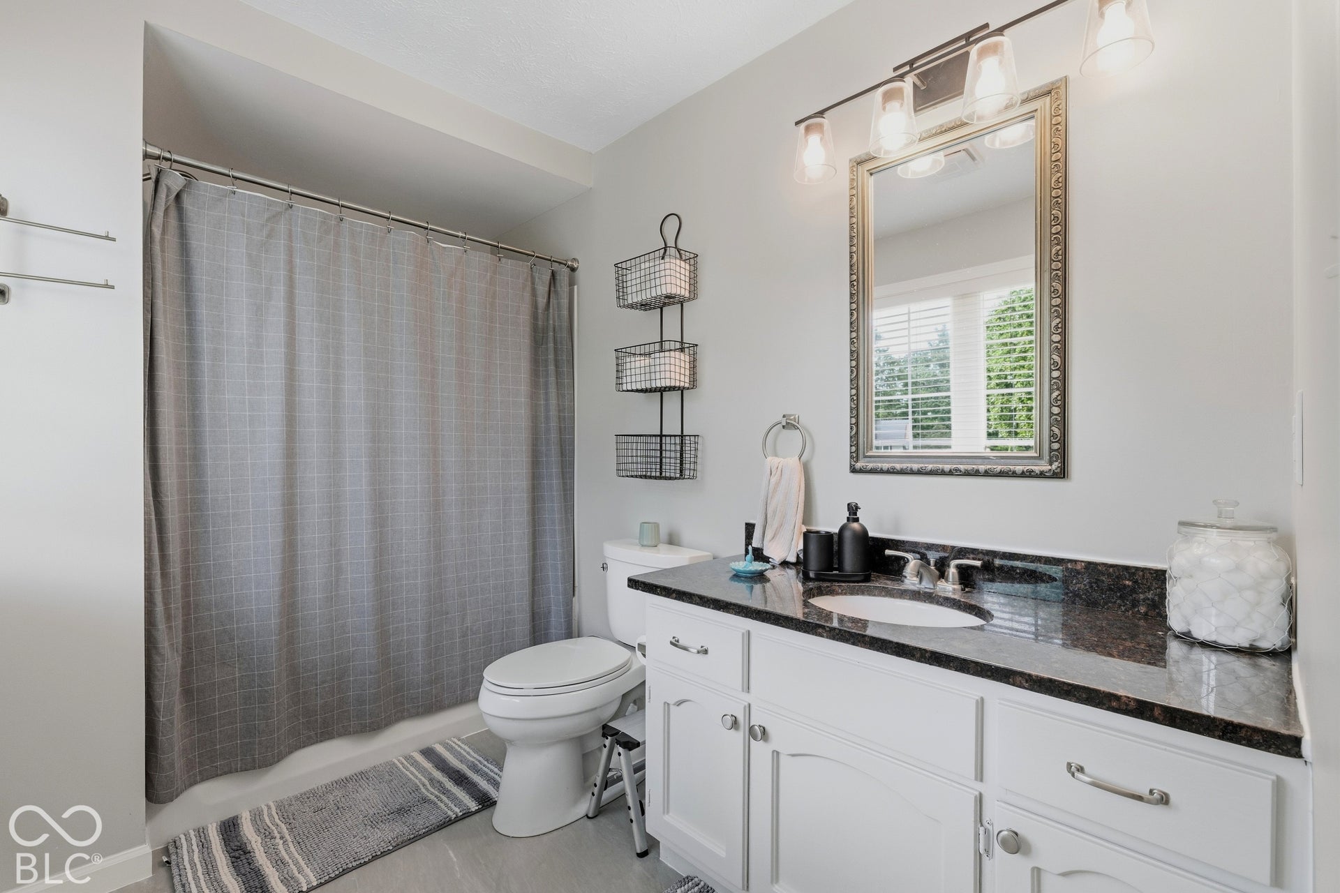 Vanity with dark countertop and undermount sink, framed mirror, and four-light fixture