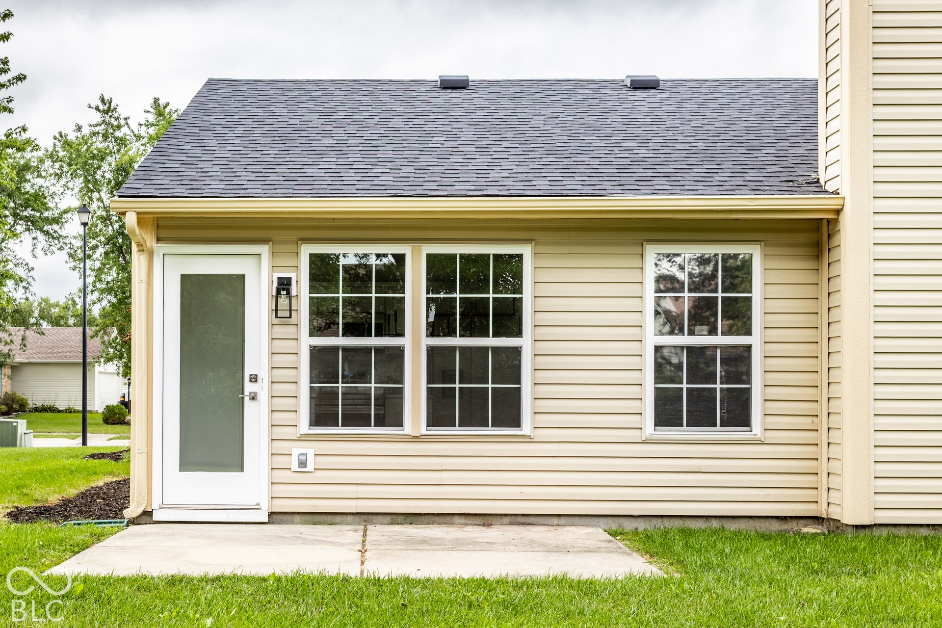 Light beige vinyl siding with a dark asphalt shingle roof