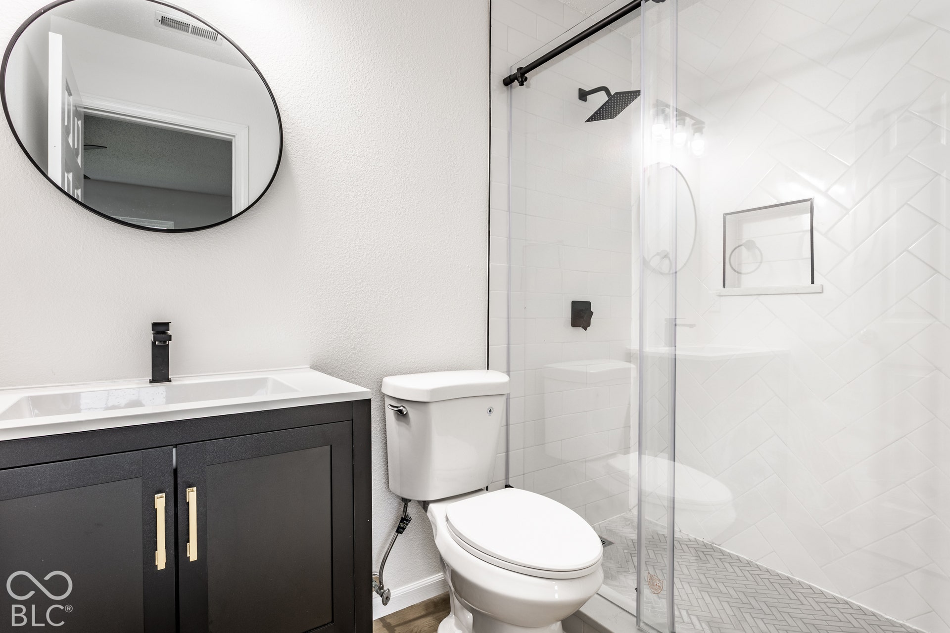 Modern vanity with a black cabinet, gold-toned hardware, and a white integrated sink