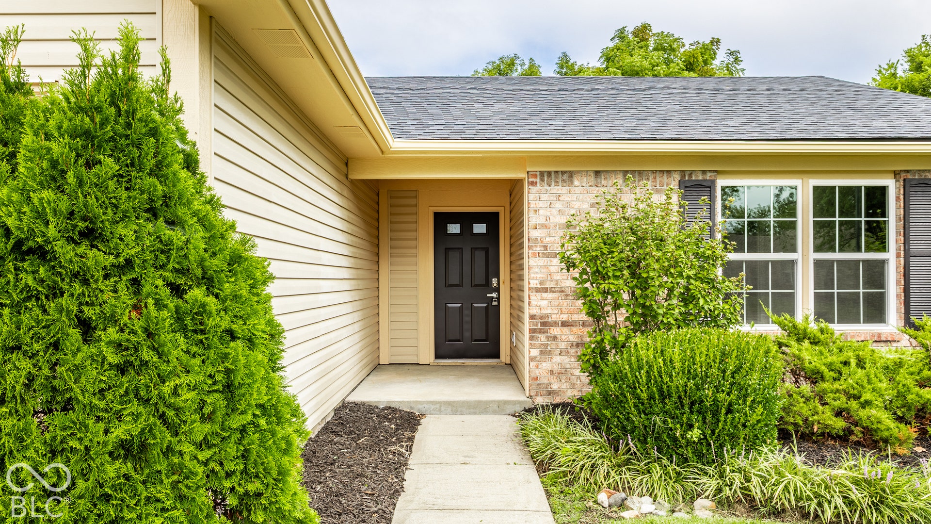 Brick and siding exterior with dark shingle roof, dark paneled entry door, and white grid windows with dark shutters
