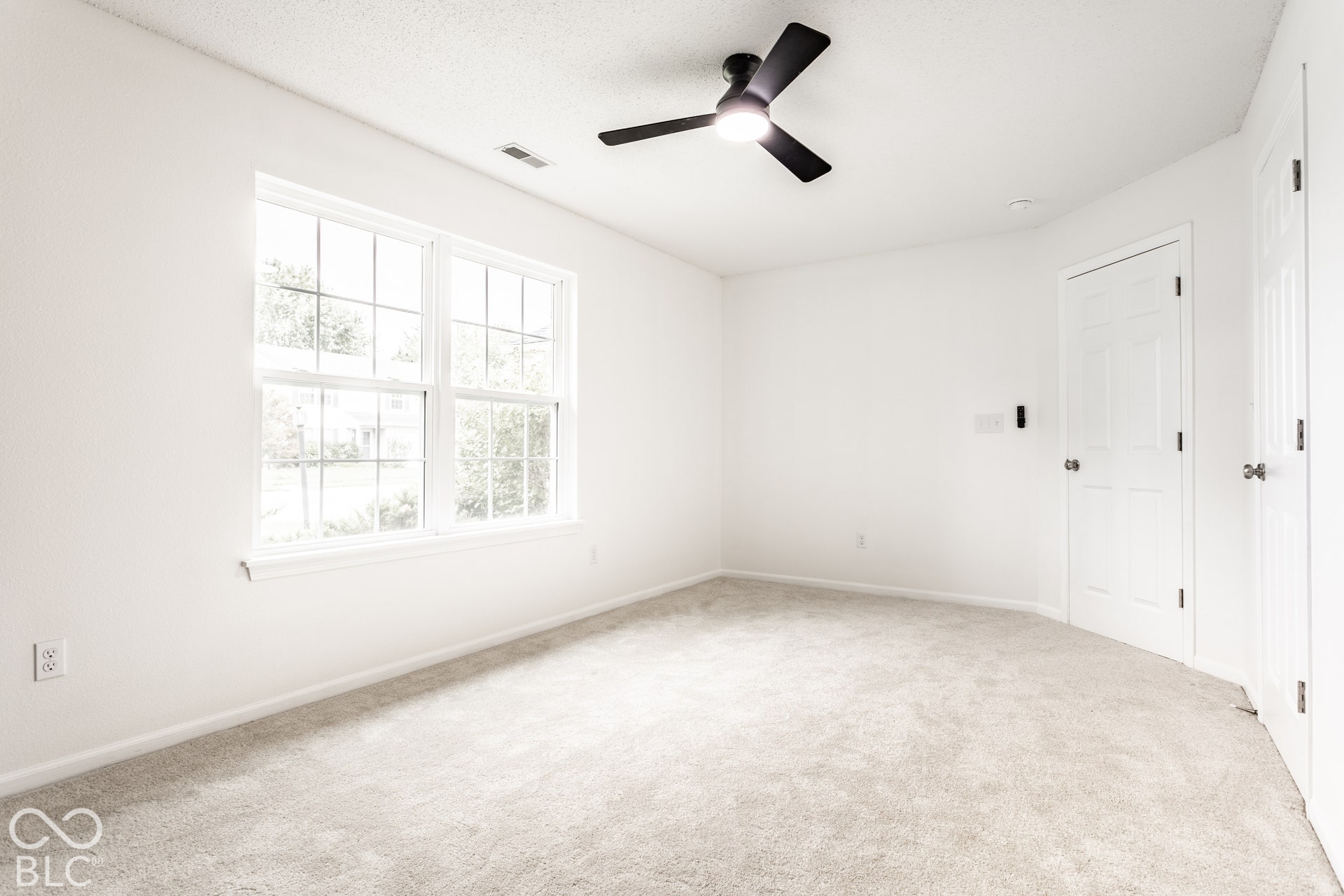 Bright room featuring wall-to-wall carpeting, a multi-pane window, and a ceiling fan with integrated lighting