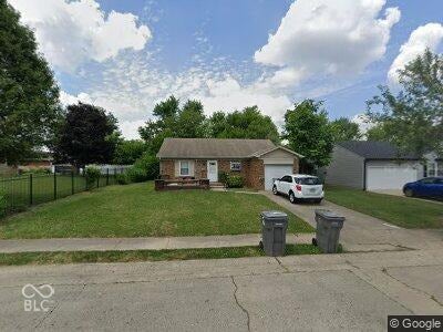 2712 Wheeler Street, Indianapolis, IN 46218 Virtually Altered - Brick exterior with an attached garage, paved driveway, and a front lawn featuring mature trees