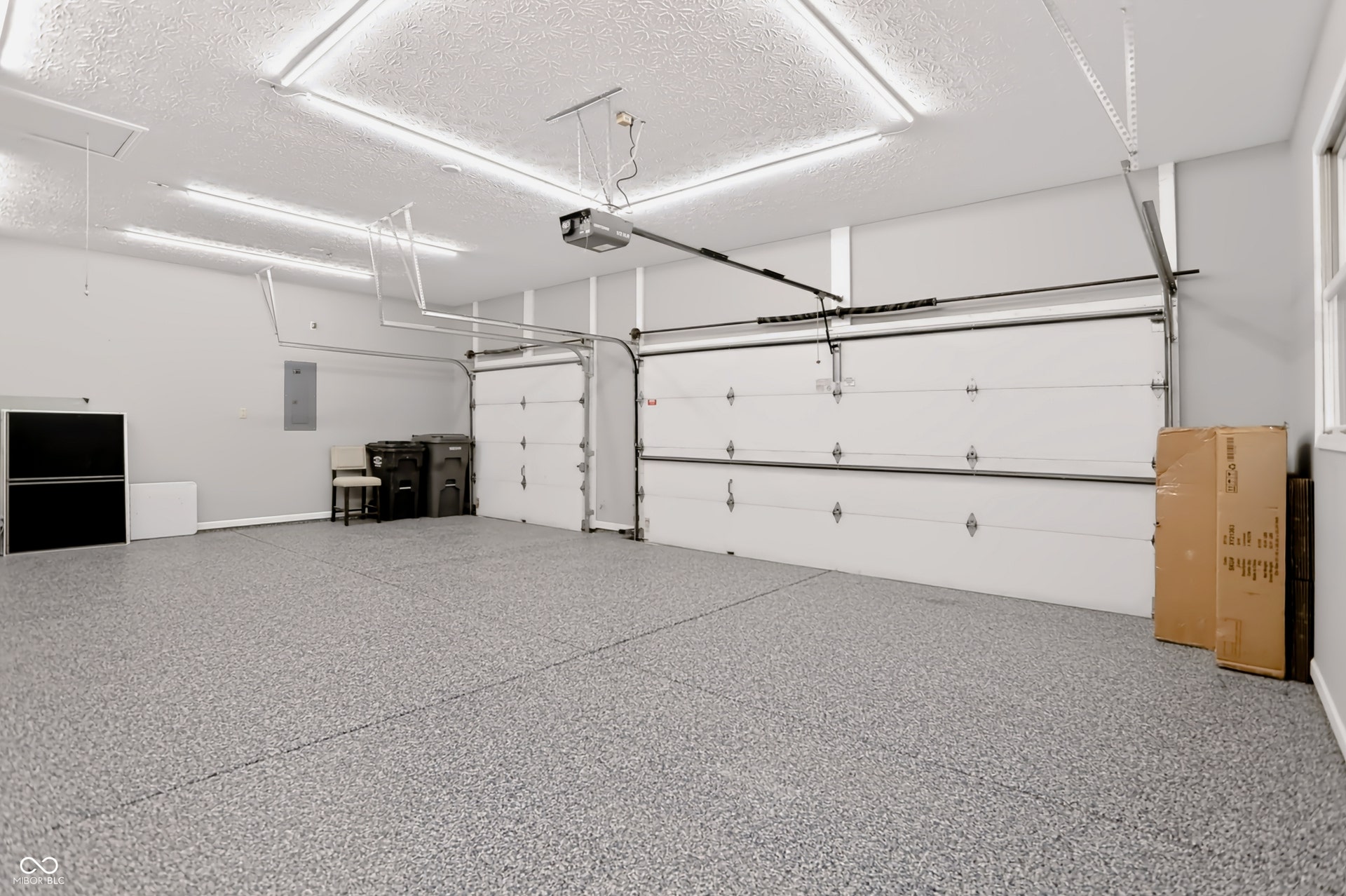 7405 Rooses Drive, Indianapolis, IN 46217 Three-car garage with epoxy flooring, multiple fluorescent light fixtures, and automatic garage door openers