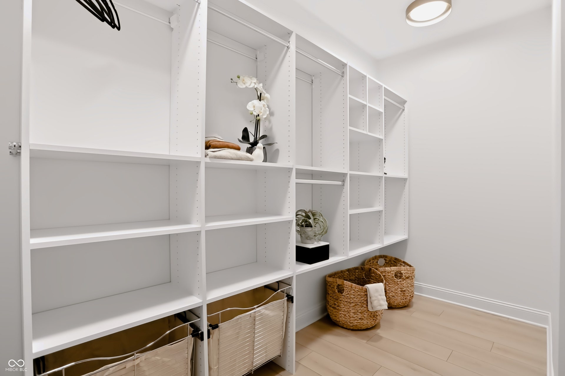 7405 Rooses Drive, Indianapolis, IN 46217 Integrated custom closet system with white shelving, multiple hanging rods, built-in cubbies, and wood-finish flooring