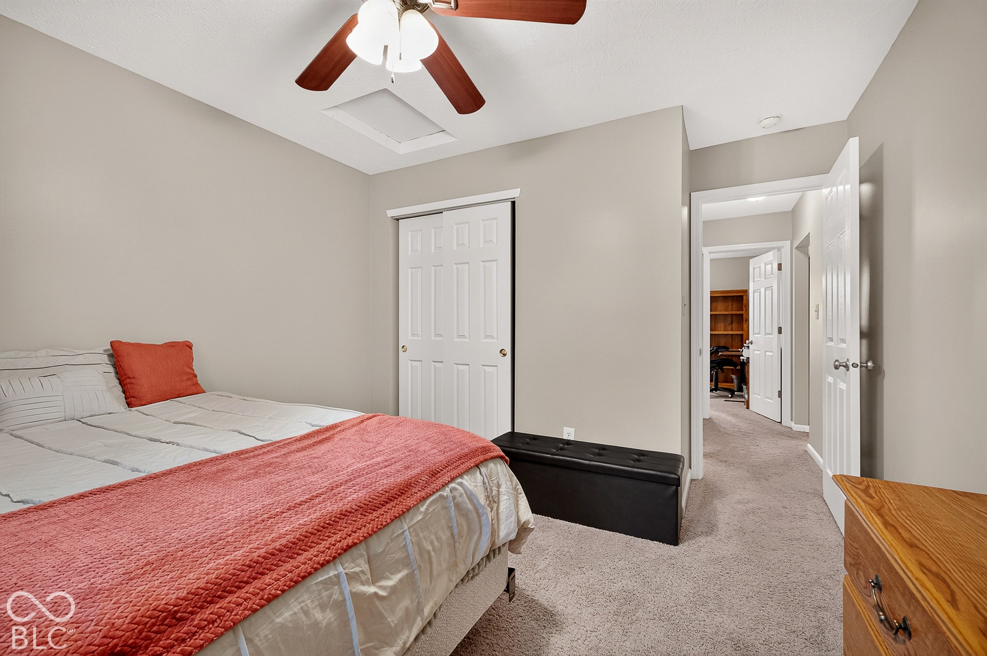 Sliding closet doors, ceiling fan with light fixture, neutral wall paint, and soft carpeting