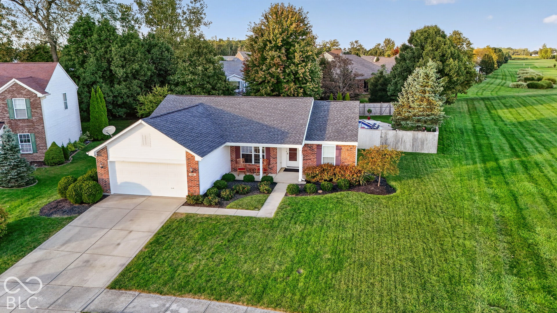 Brick and siding exterior with a two-car garage, concrete driveway, and established landscaping
