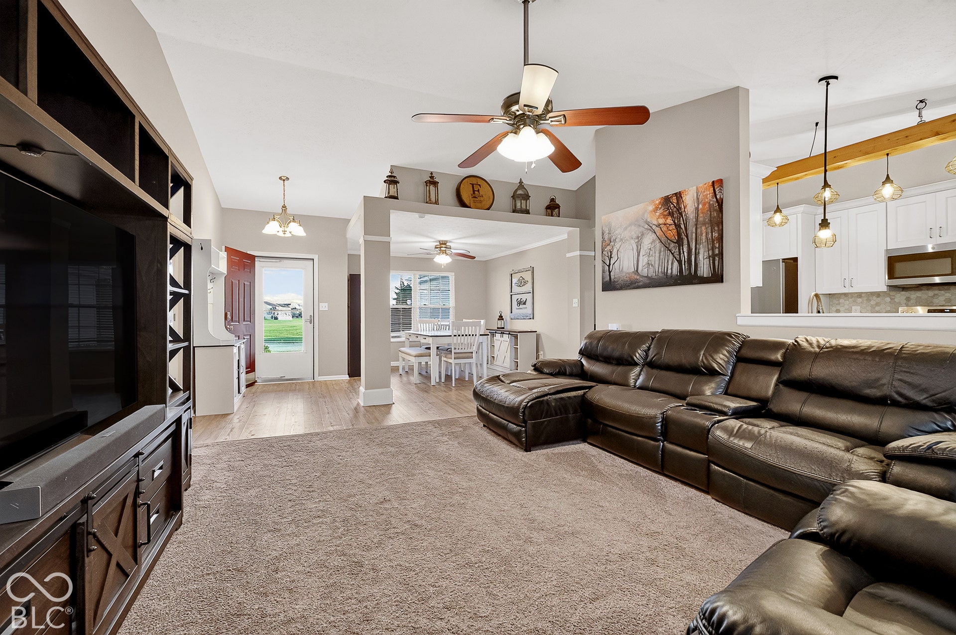Vaulted ceiling with a ceiling fan, wood-finish flooring, and a built-in media center