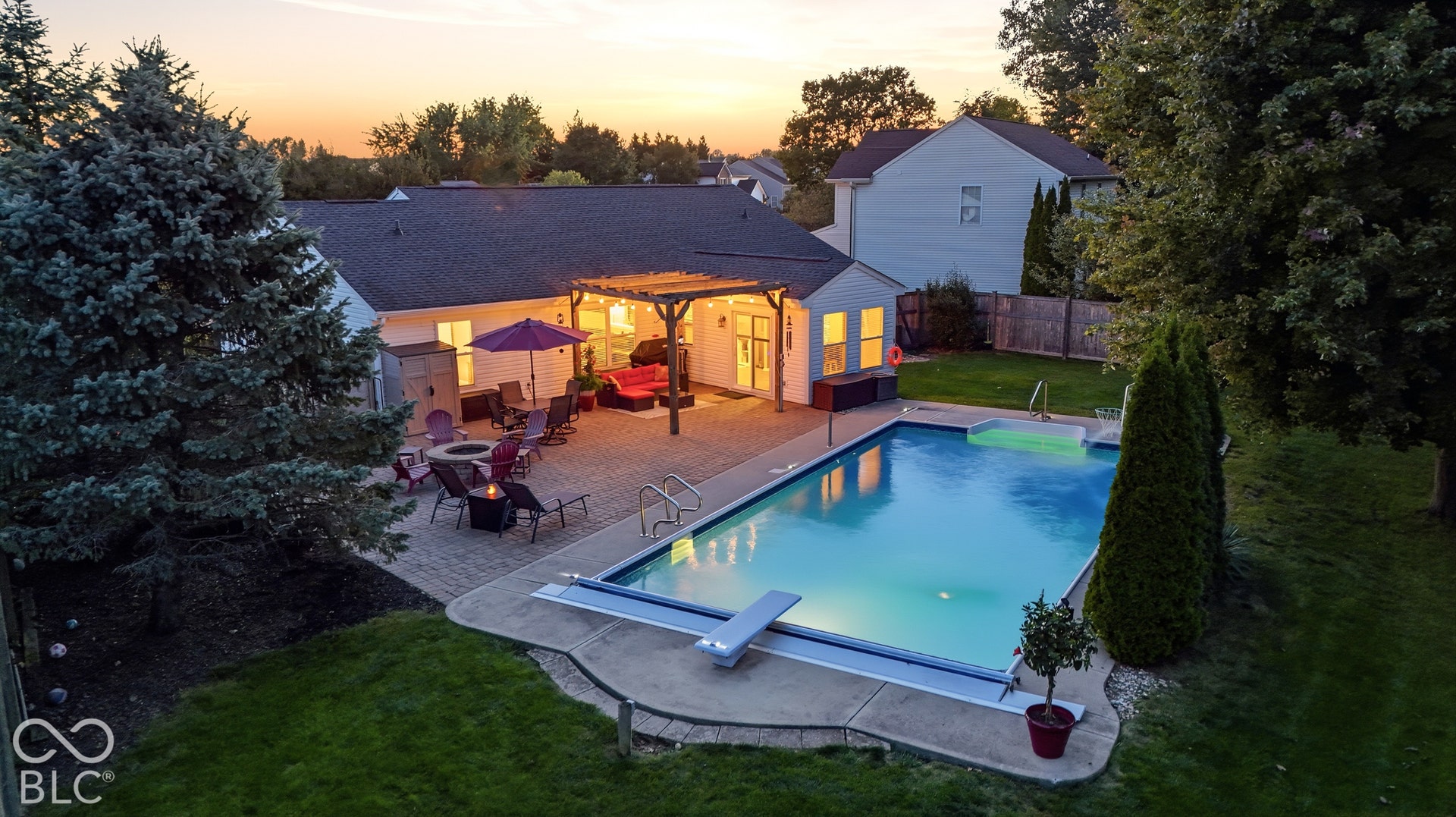 Expansive backyard featuring a large swimming pool with a diving board, a paved patio, and a pergola structure