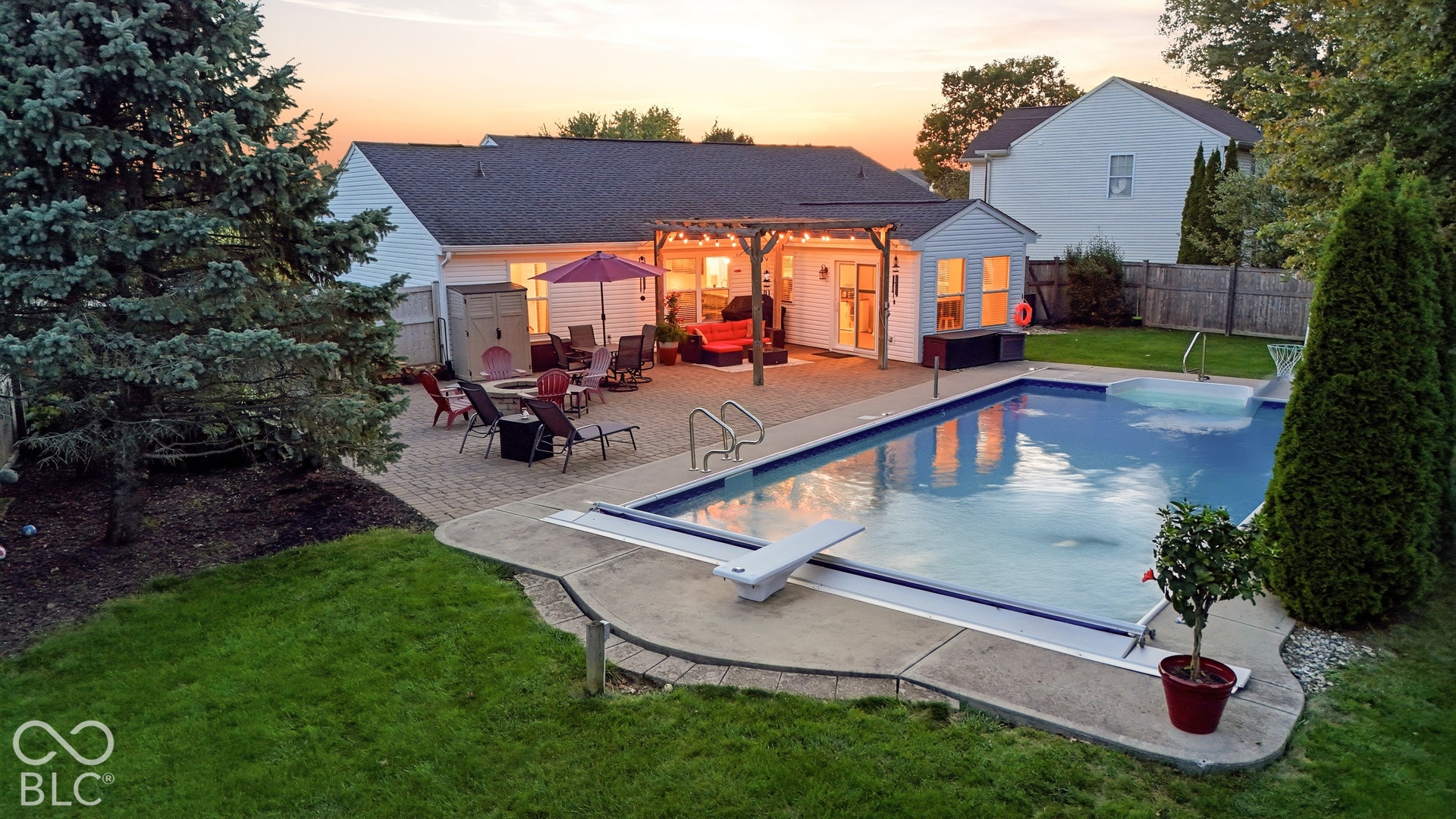 In-ground swimming pool with diving board, expansive paver patio, built-in pergola, and detached pool house