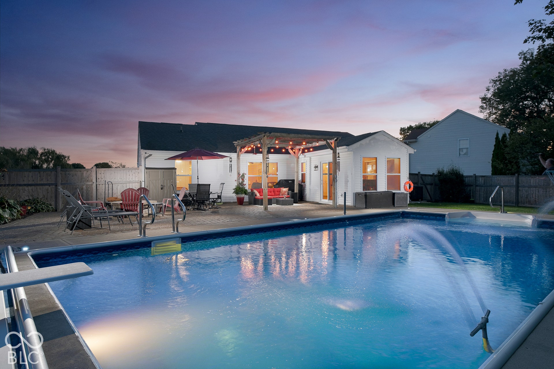 In-ground swimming pool with diving board, surrounded by a paved patio