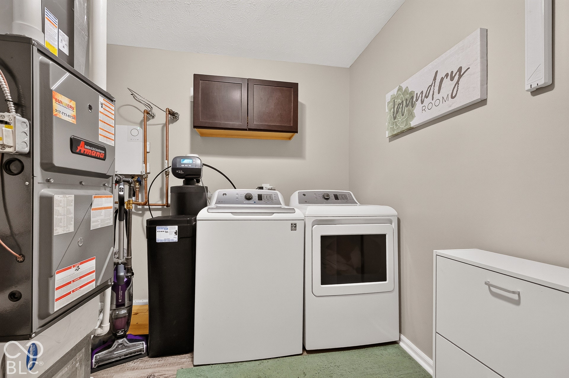 Utility area with wood-finish flooring, built-in dark wood-finish cabinetry, and light neutral wall paint