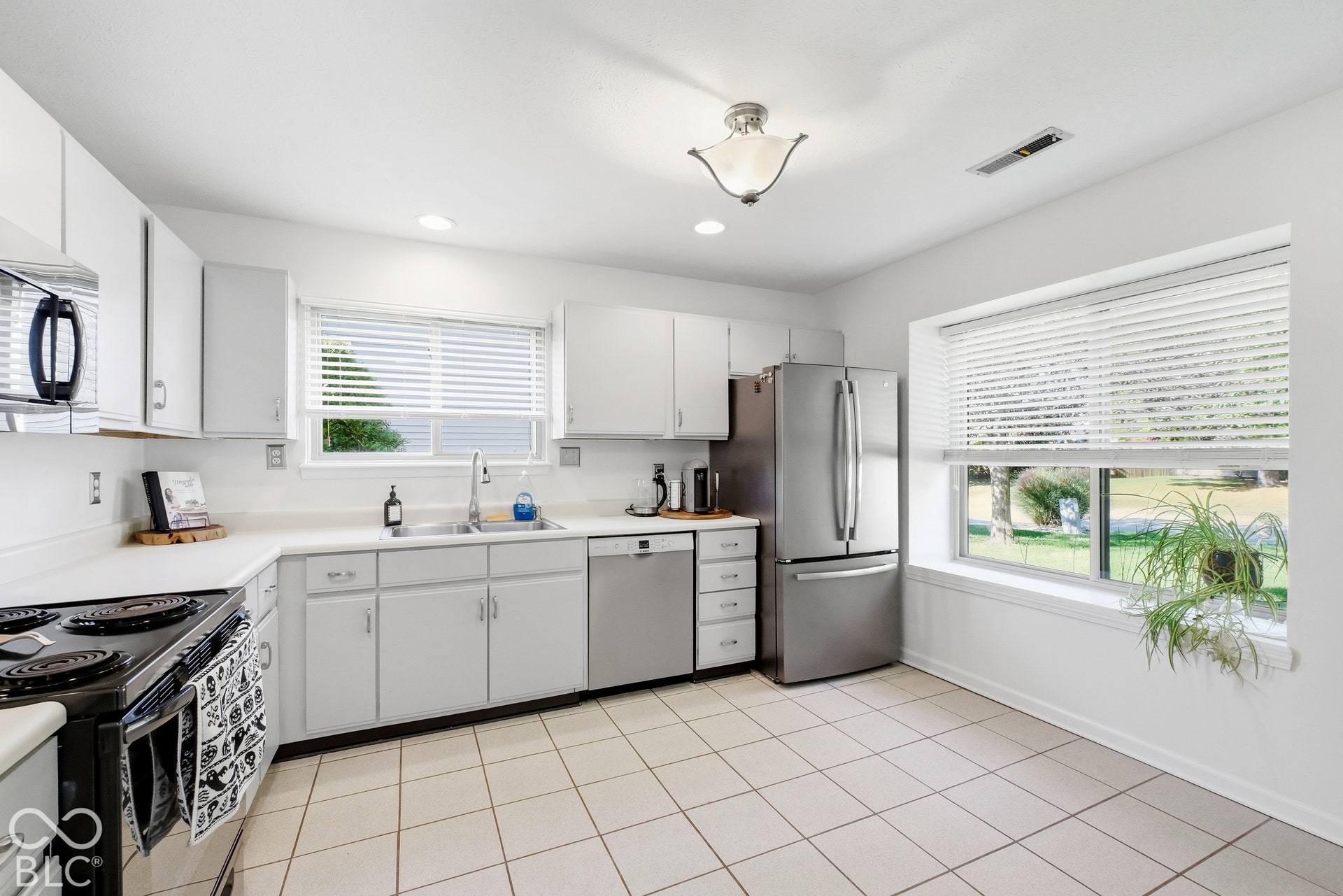 White cabinetry with coordinating countertops, stainless steel appliances, and tile flooring