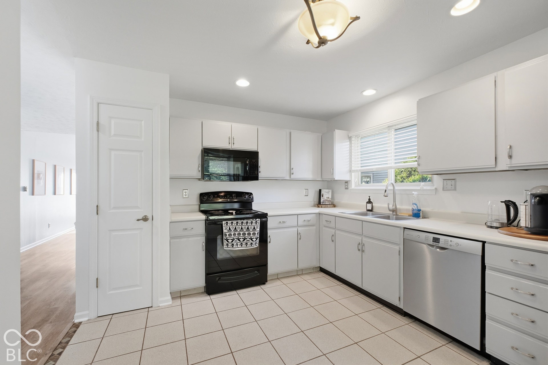 White cabinetry with stainless steel appliances, tile flooring, and recessed lighting