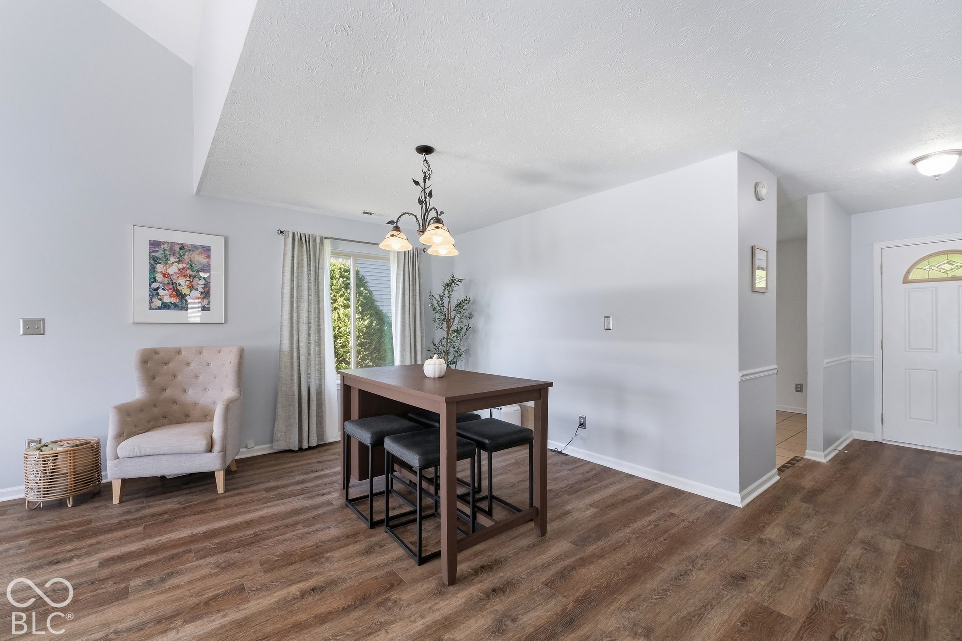 Wood-finish flooring, vaulted ceiling, built-in wall niche, and panel front door with arched glass insert