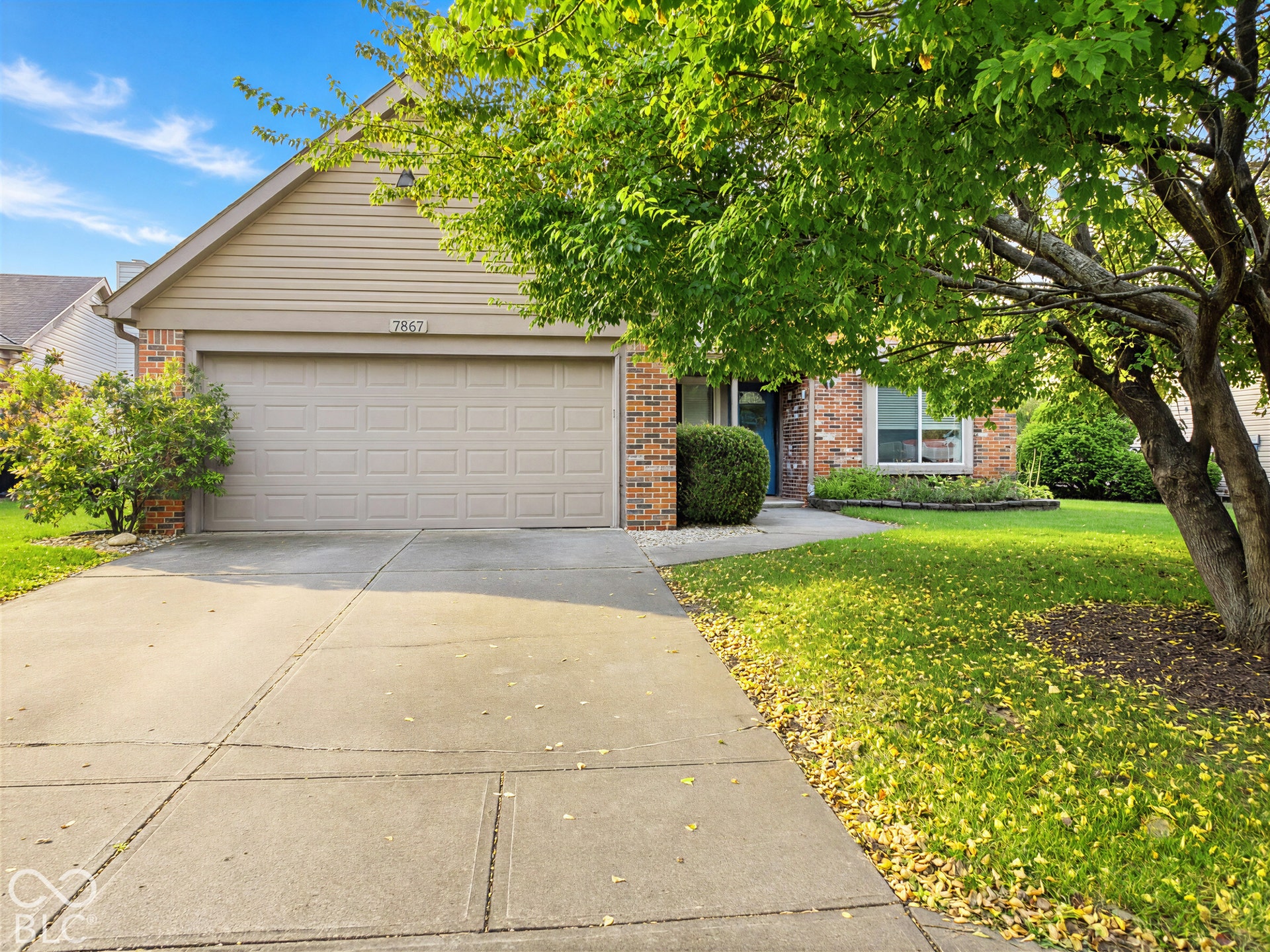 Brick and siding exterior with an attached garage, concrete driveway, and established landscaping
