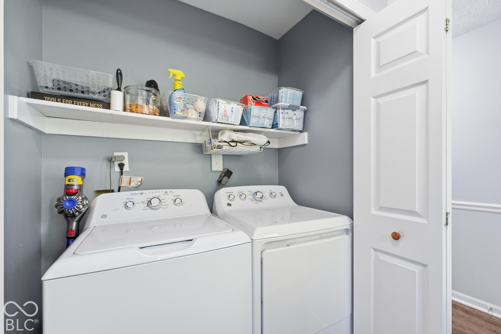 Laundry area with built-in shelving, a white paneled door, and light gray wall paint