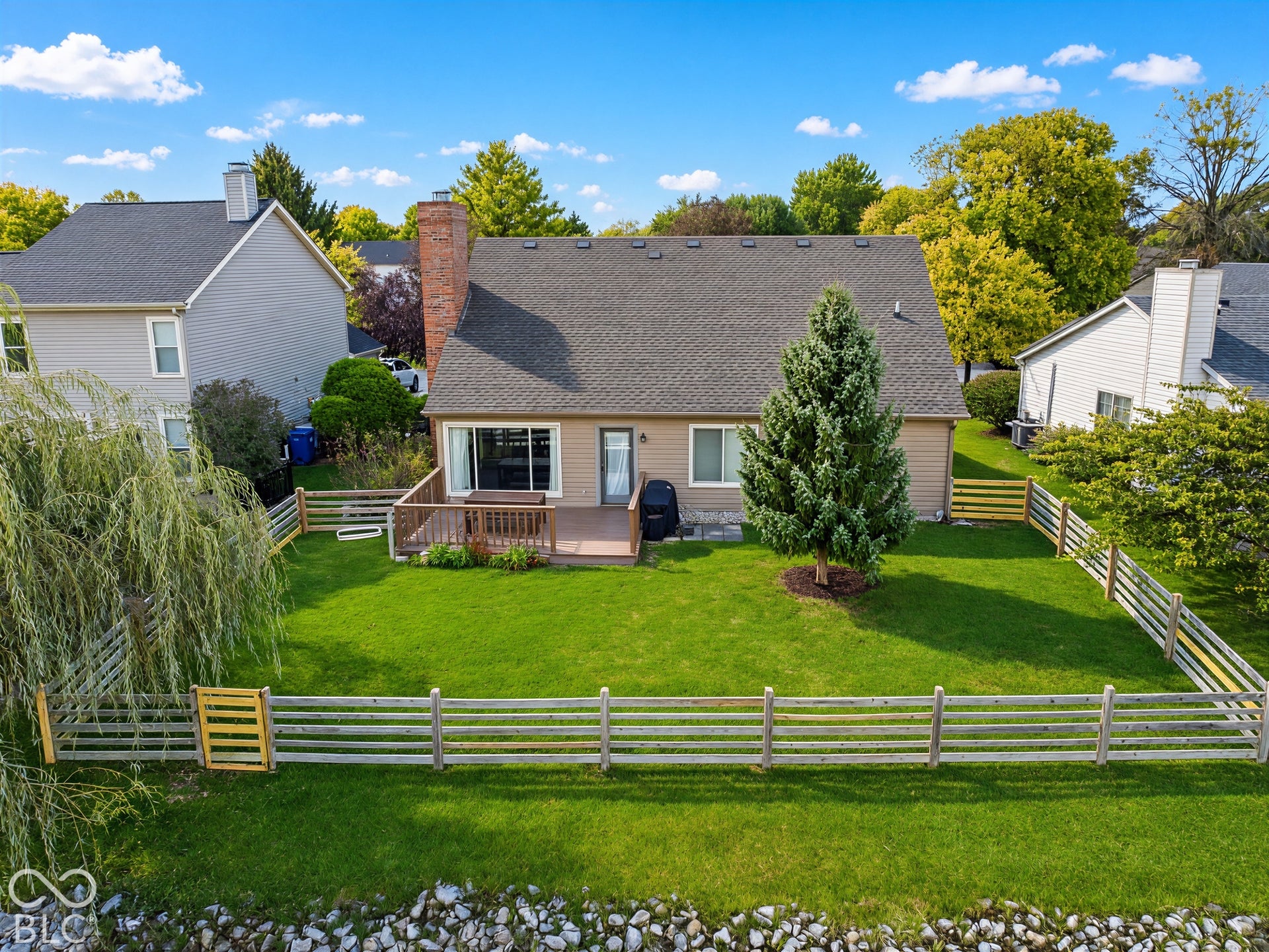 Rear exterior with a wood deck, sliding glass door, and a brick chimney