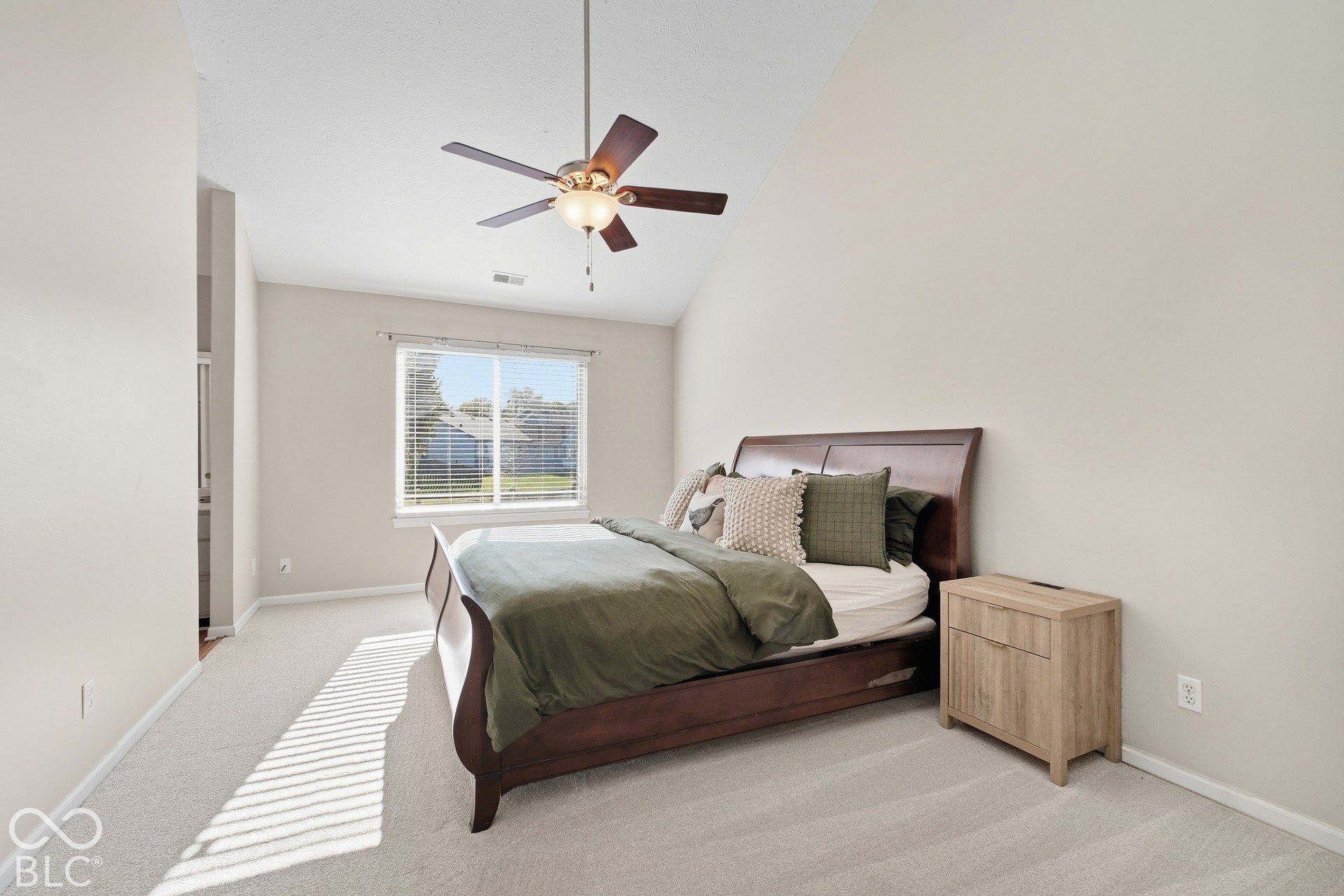 Vaulted ceiling with a ceiling fan, neutral wall paint, and carpet flooring