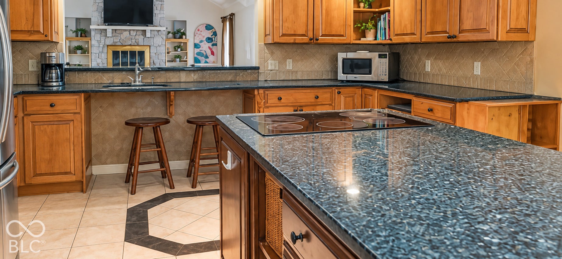 Kitchen featuring wood cabinetry, dark-finish granite countertops, tile flooring with an octagonal inlay, a built-in cooktop, and a double basin sink