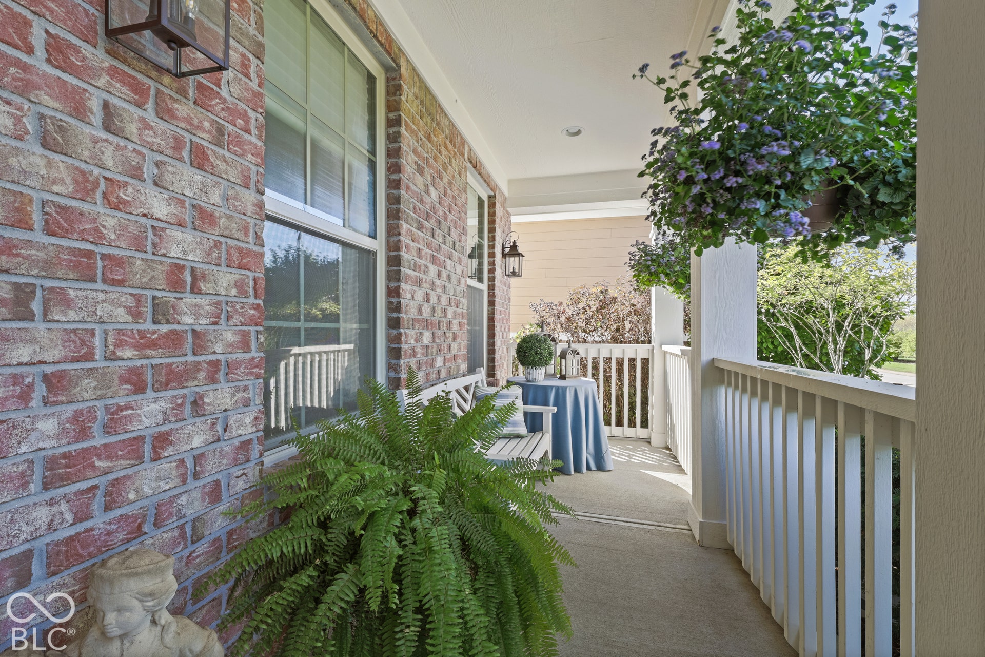 Virtually Altered - Brick exterior with white-framed windows, a covered front porch, and white balustrade railings