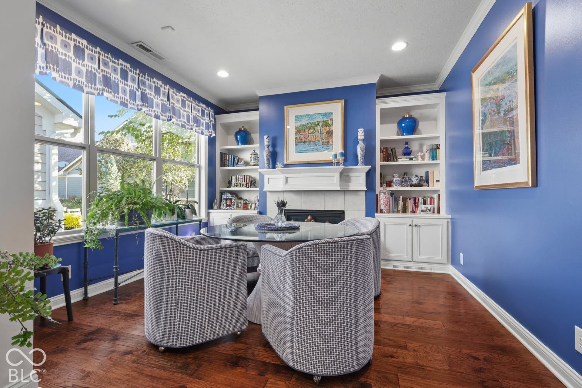 Hardwood-finish flooring, built-in shelving, white fireplace mantel, and crown molding