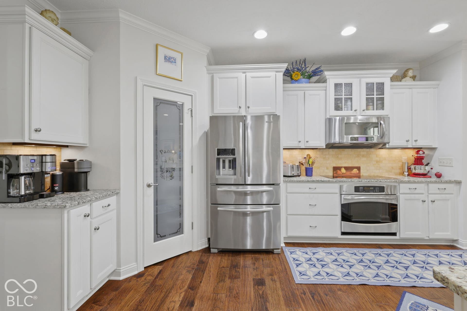 Kitchen featuring wood-finish flooring, white cabinetry, stainless steel appliances, granite countertops, and recessed lighting