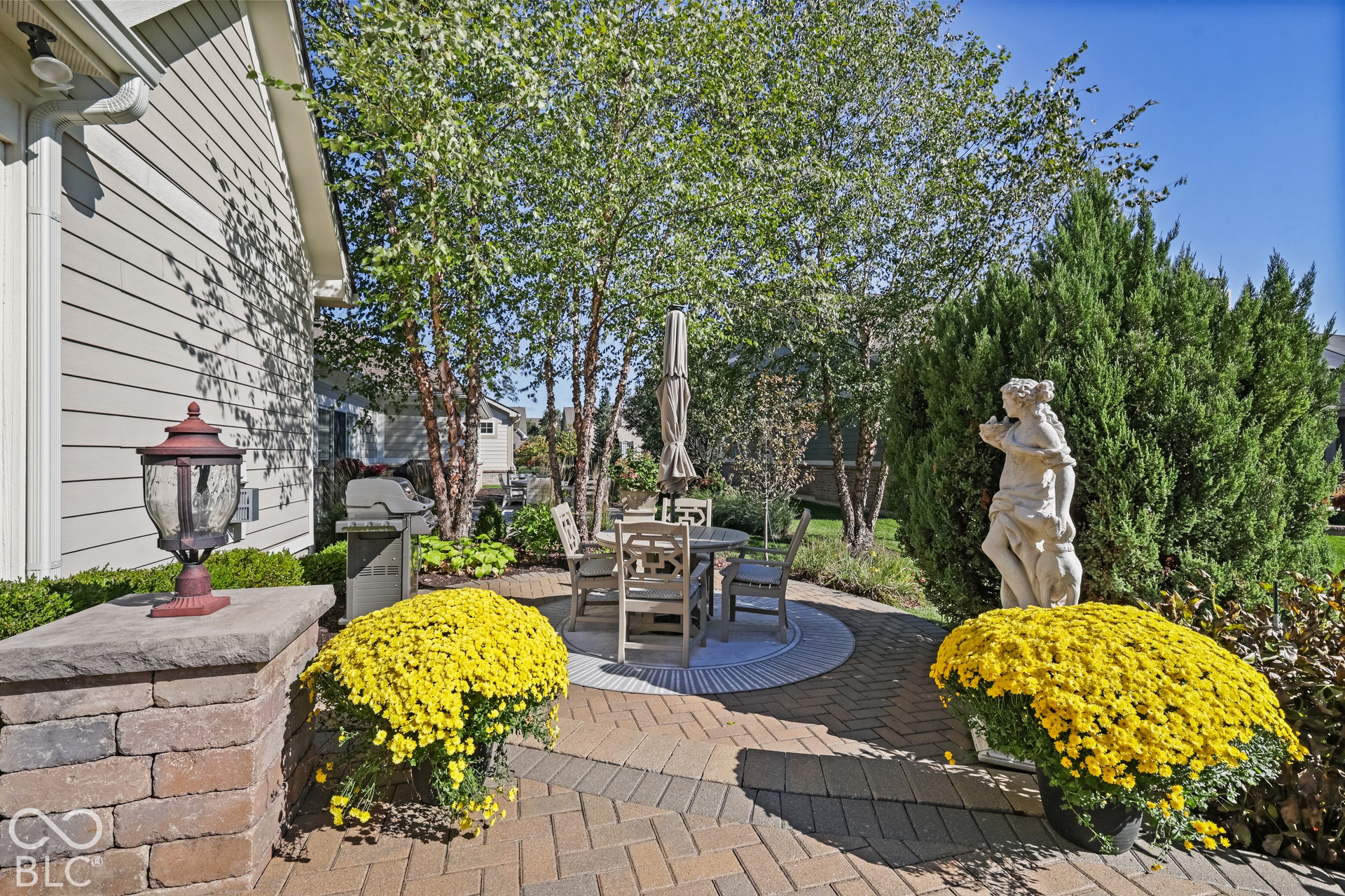 Virtually Altered - Paved patio with decorative brickwork, surrounded by mature trees and shrubs