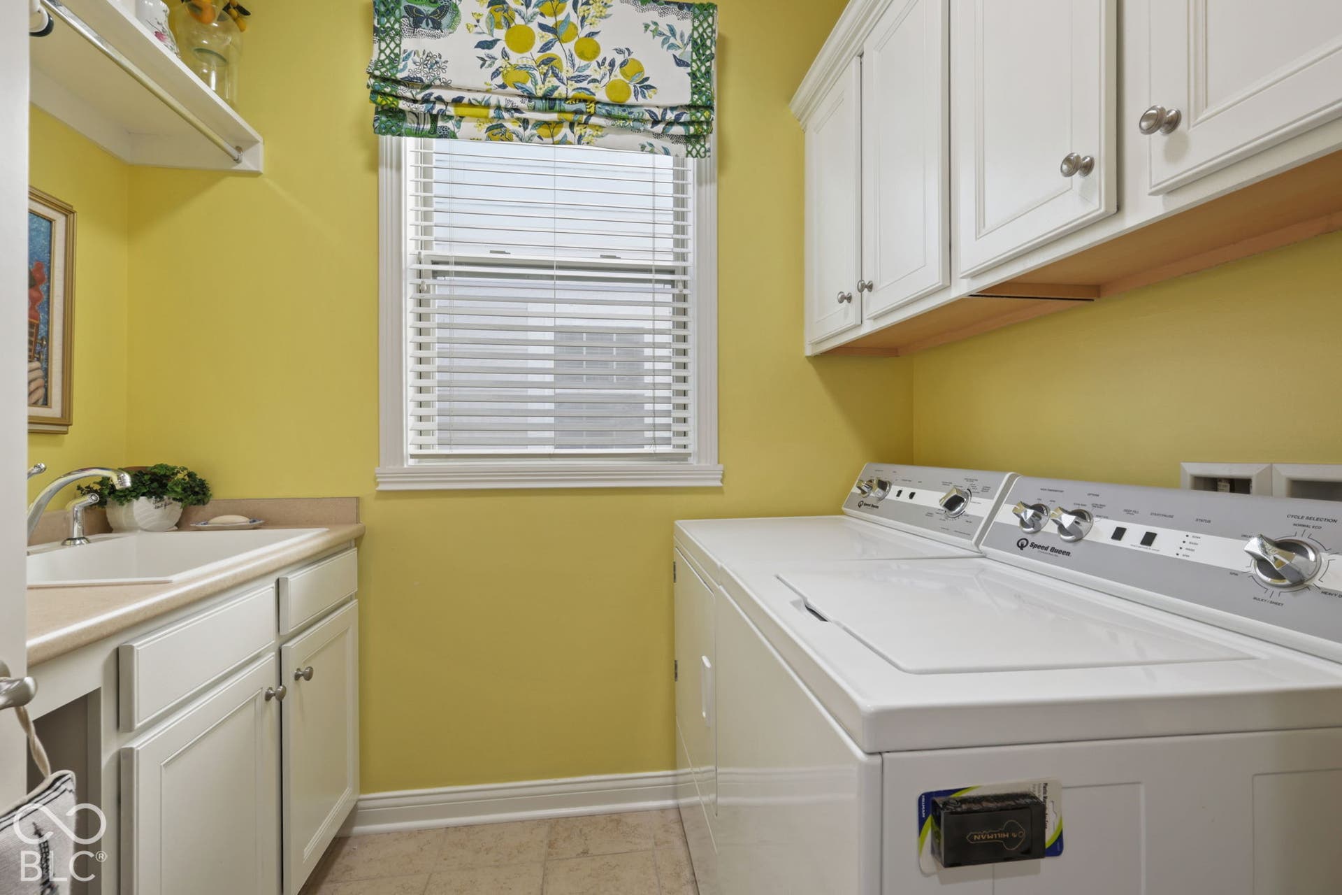 Windowed utility room featuring white cabinetry, a built-in sink, and light-toned flooring