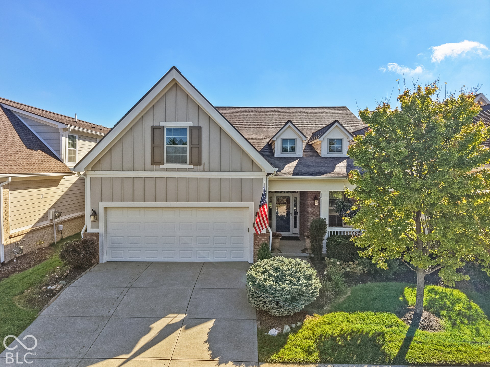 Virtually Altered - Two-story residence featuring a two-car garage, dormer windows, and a covered porch with a white railing