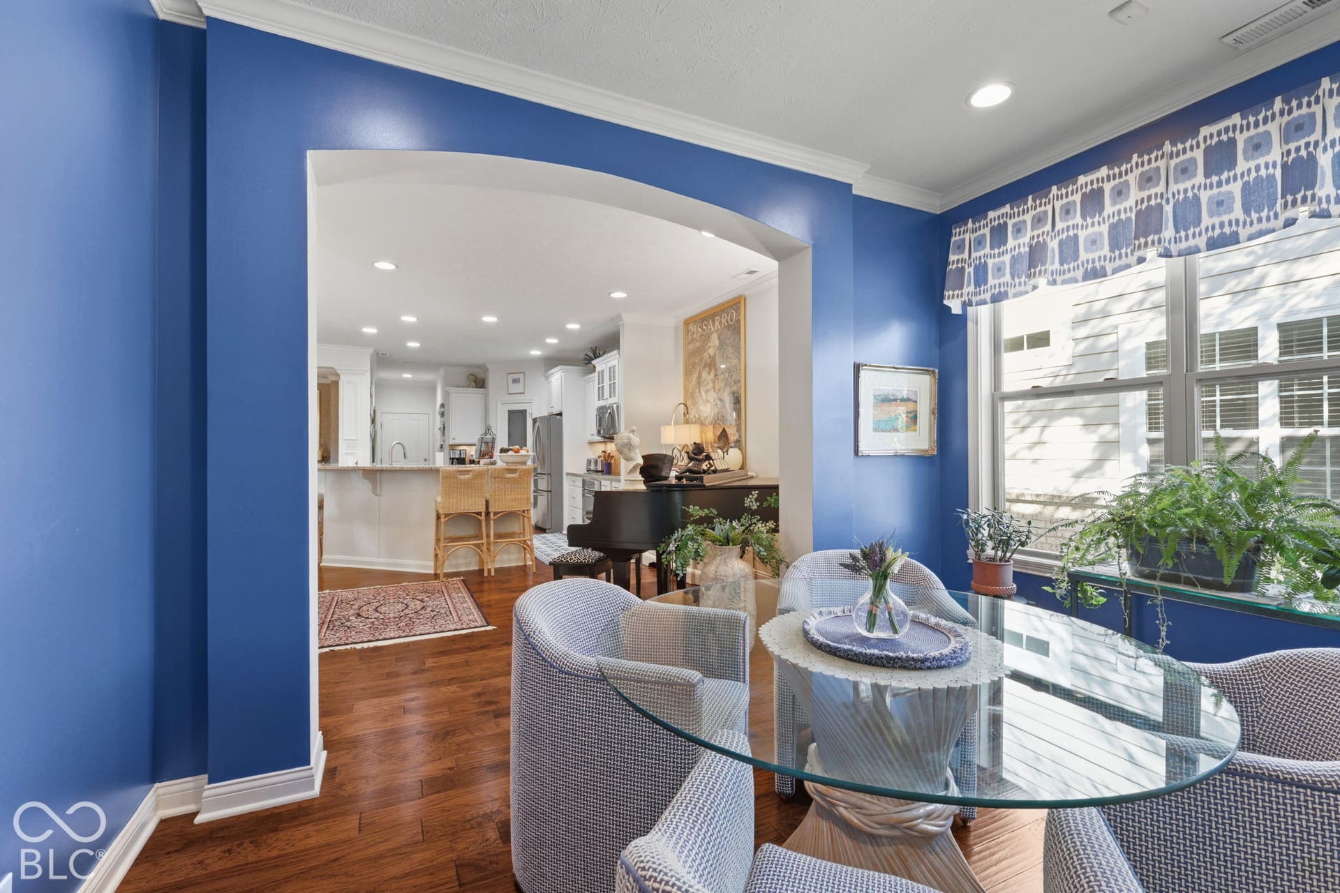 Arched entry to the kitchen featuring recessed lighting, a built-in breakfast bar, and wood-finish flooring