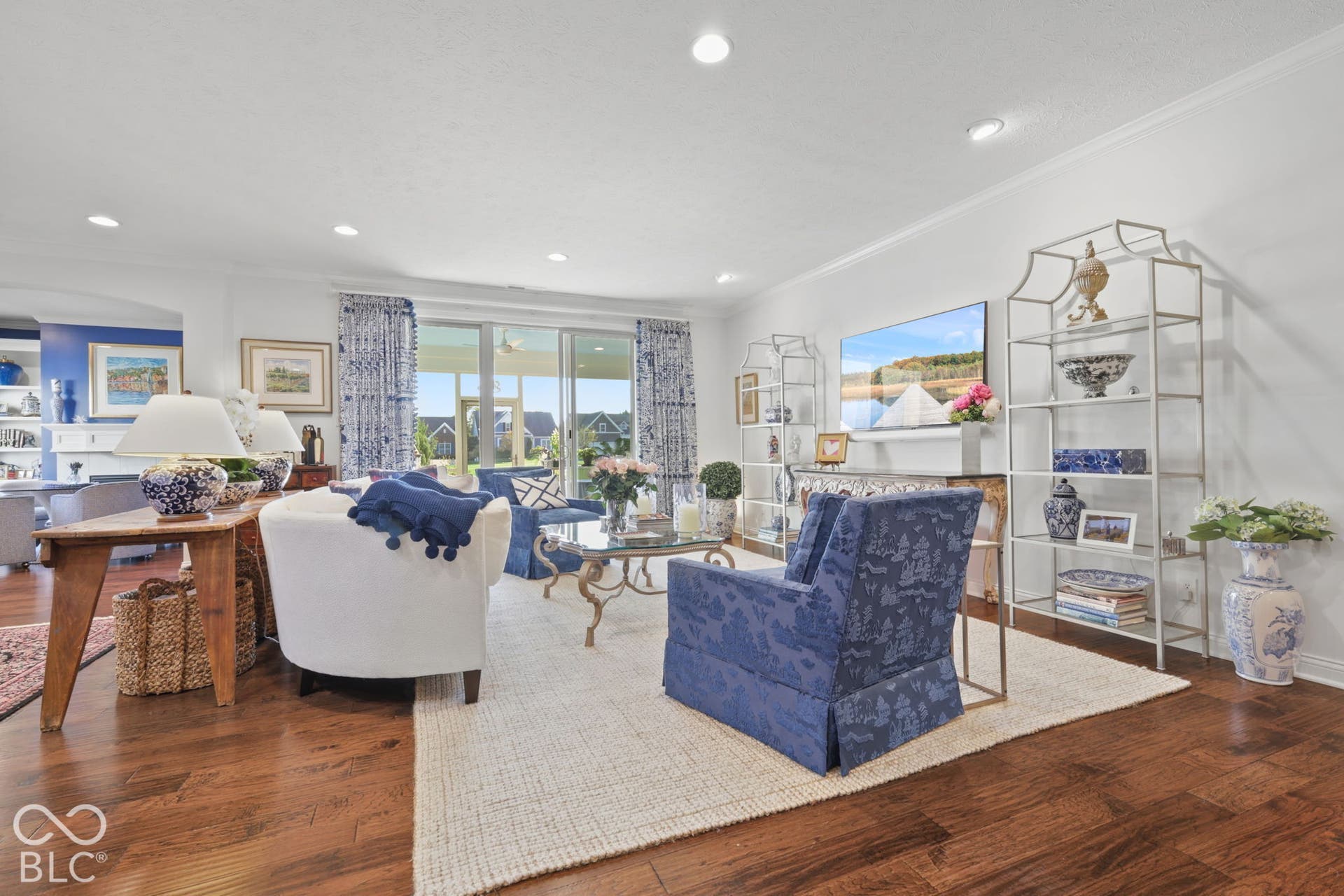 Hardwood flooring, recessed lighting, white crown molding, built-in shelving, and sliding glass doors to outdoor area
