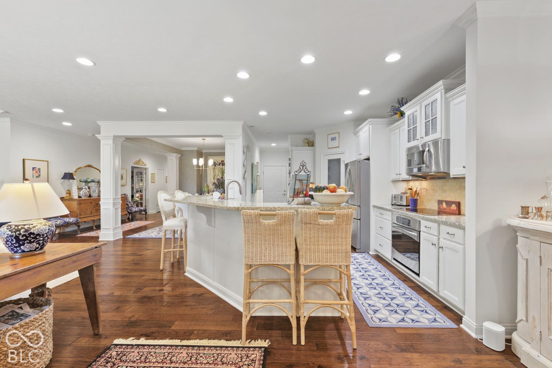 Kitchen featuring a stone countertop island with seating, white cabinetry, stainless steel appliances, and wood-finish flooring
