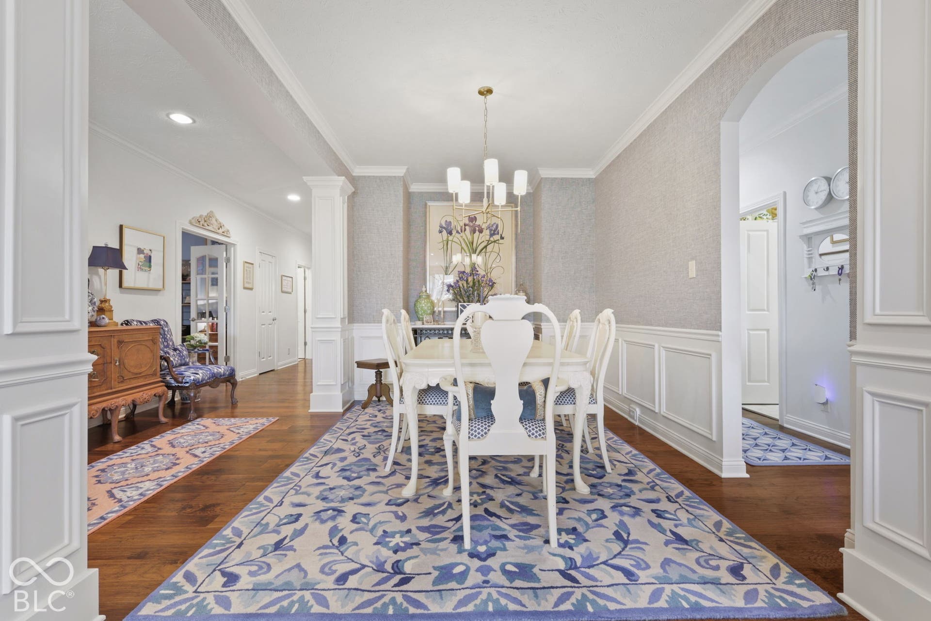 Hardwood flooring throughout, wainscoting, crown molding, and an arched doorway