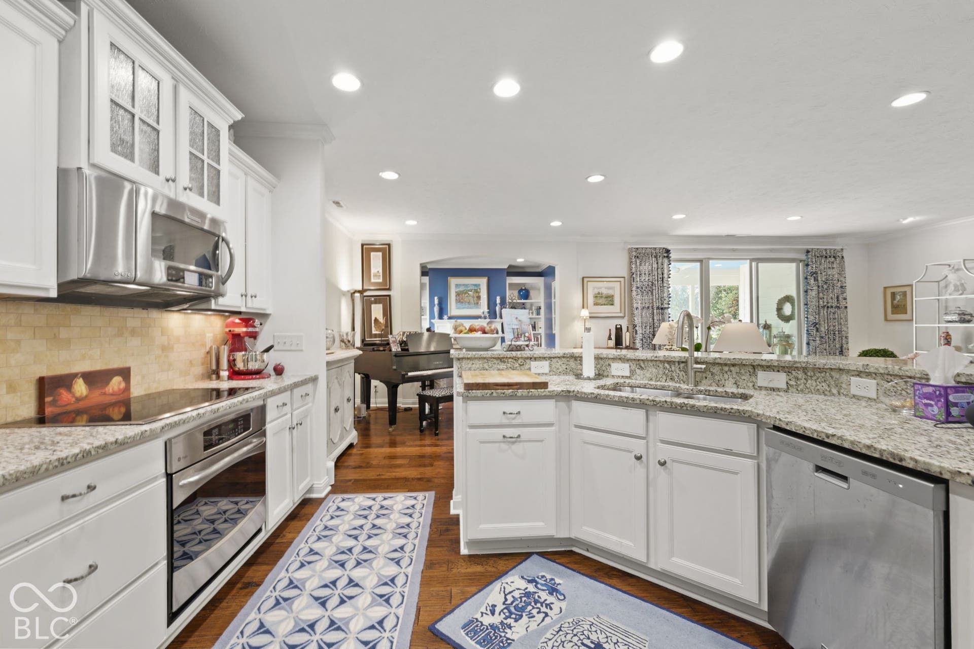 White cabinetry, stainless steel appliances, speckled stone countertops, wood-finish flooring, and recessed lighting