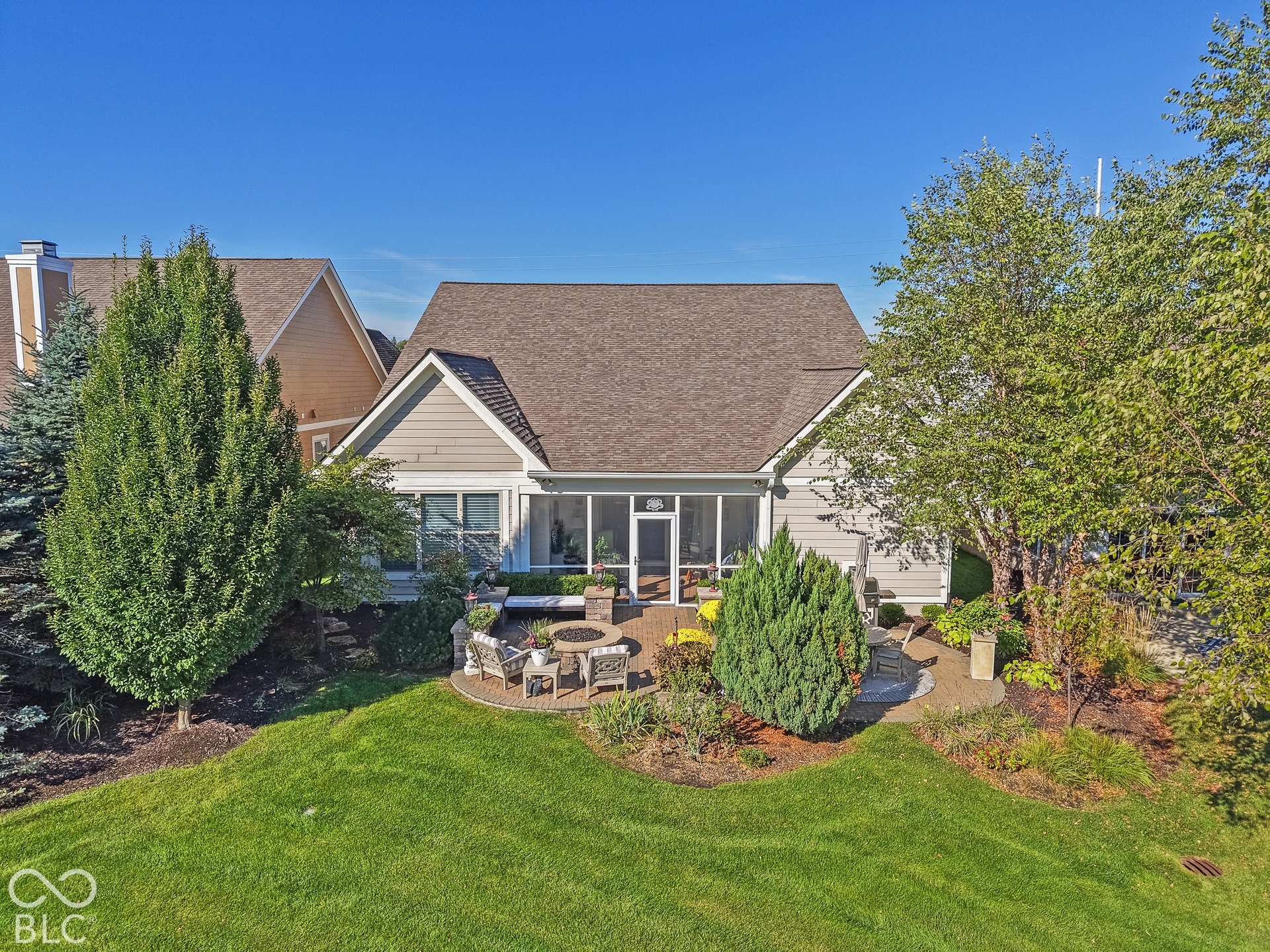 Virtually Altered - Manicured lawn with a screened-in porch, patio, and built-in fire pit
