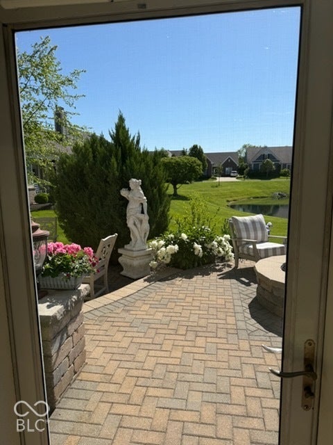 Brick paver patio featuring a stone-clad fire pit and decorative plantings